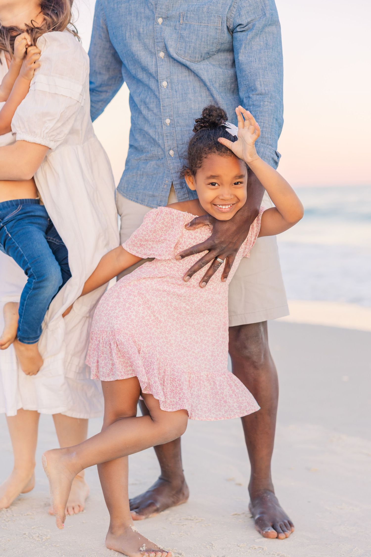 Candid family moment captured at beach level showing playful interactions and bare feet in the sand.