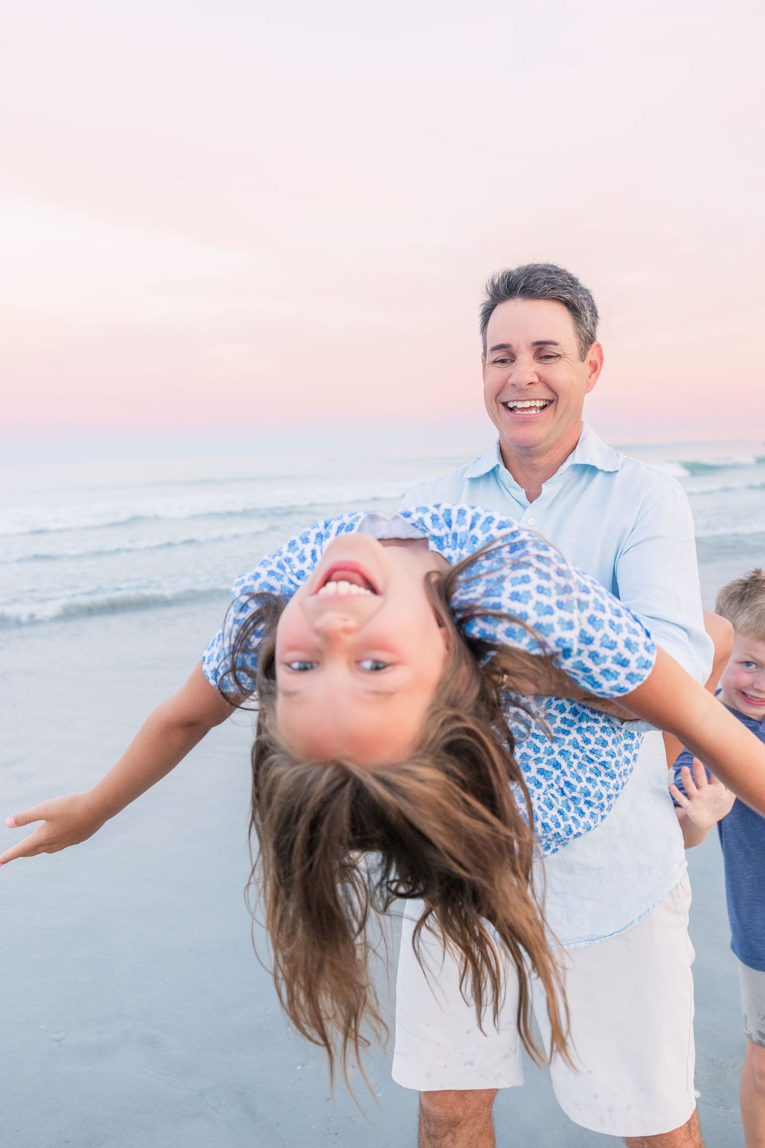 Playful beach poses captured during a family photoshoot at sunset.