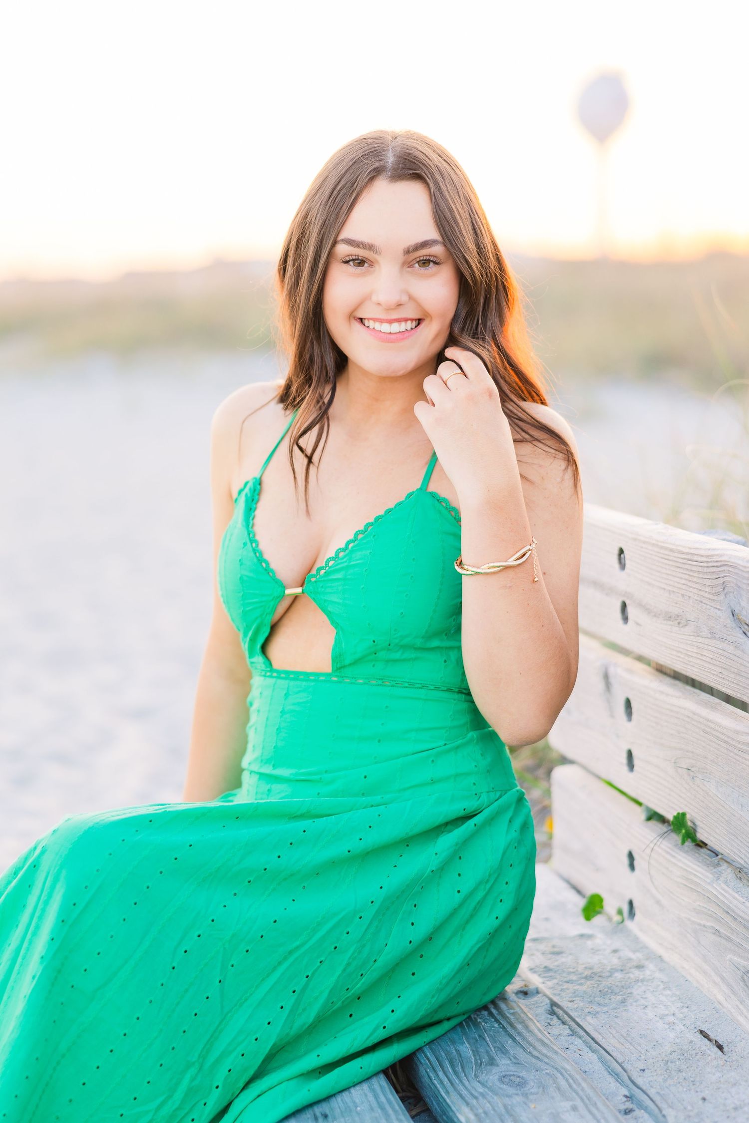 Casual beach photoshoot with a bright green dress on a wooden boardwalk.