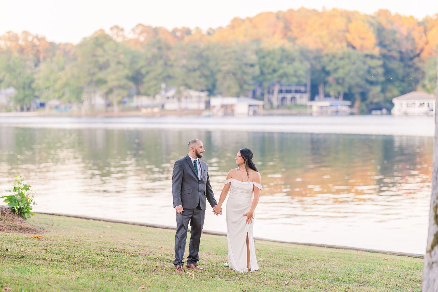 A romantic lakeside photo session during golden hour with fall foliage in the background.