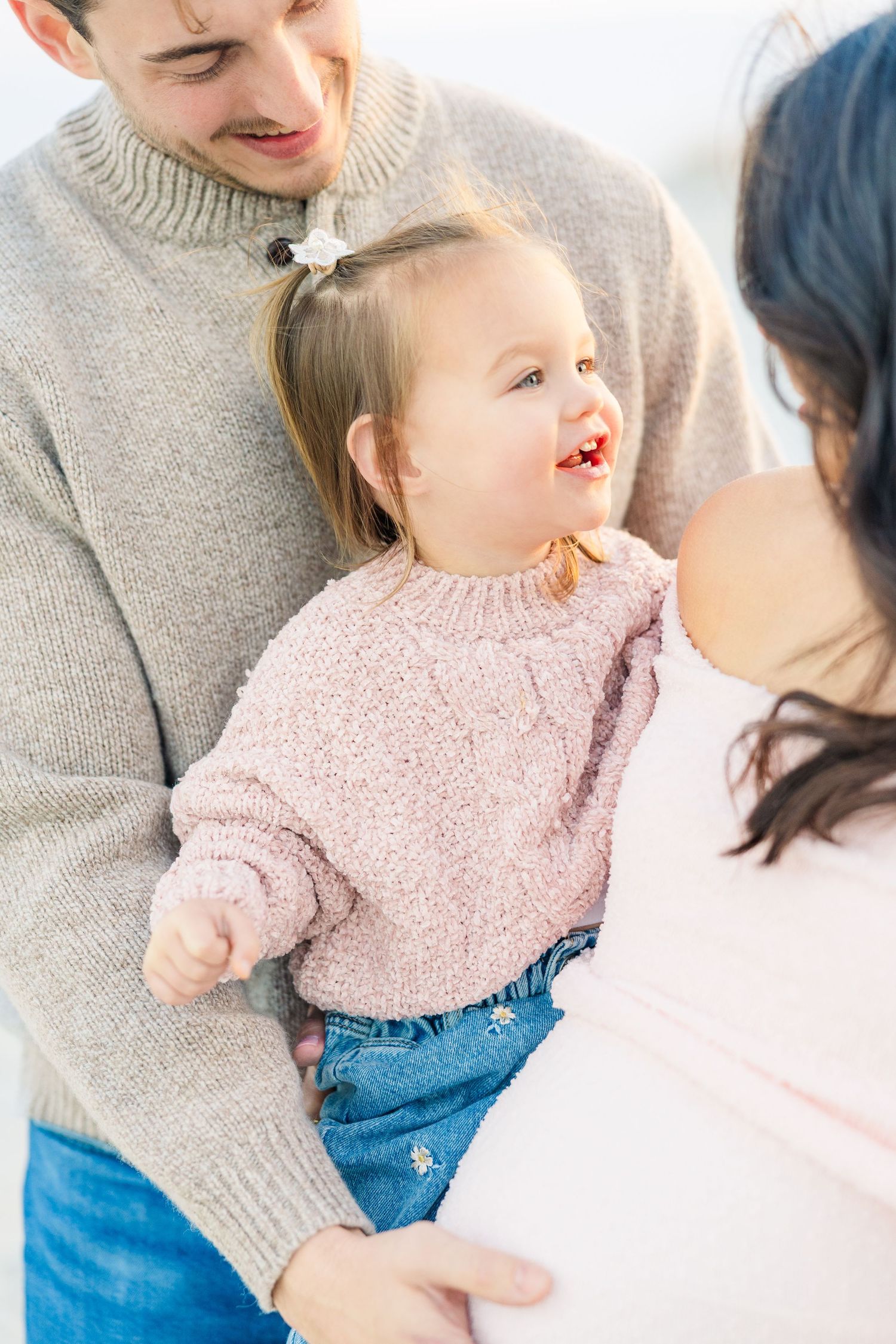 Close-up beach portraits showing joyful expressions and soft pink sweater details.