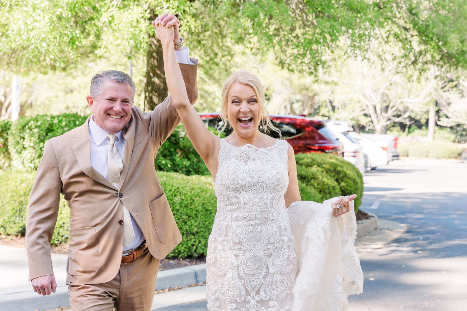 Outdoor wedding photography session with couple and wedding party under sunlit trees.