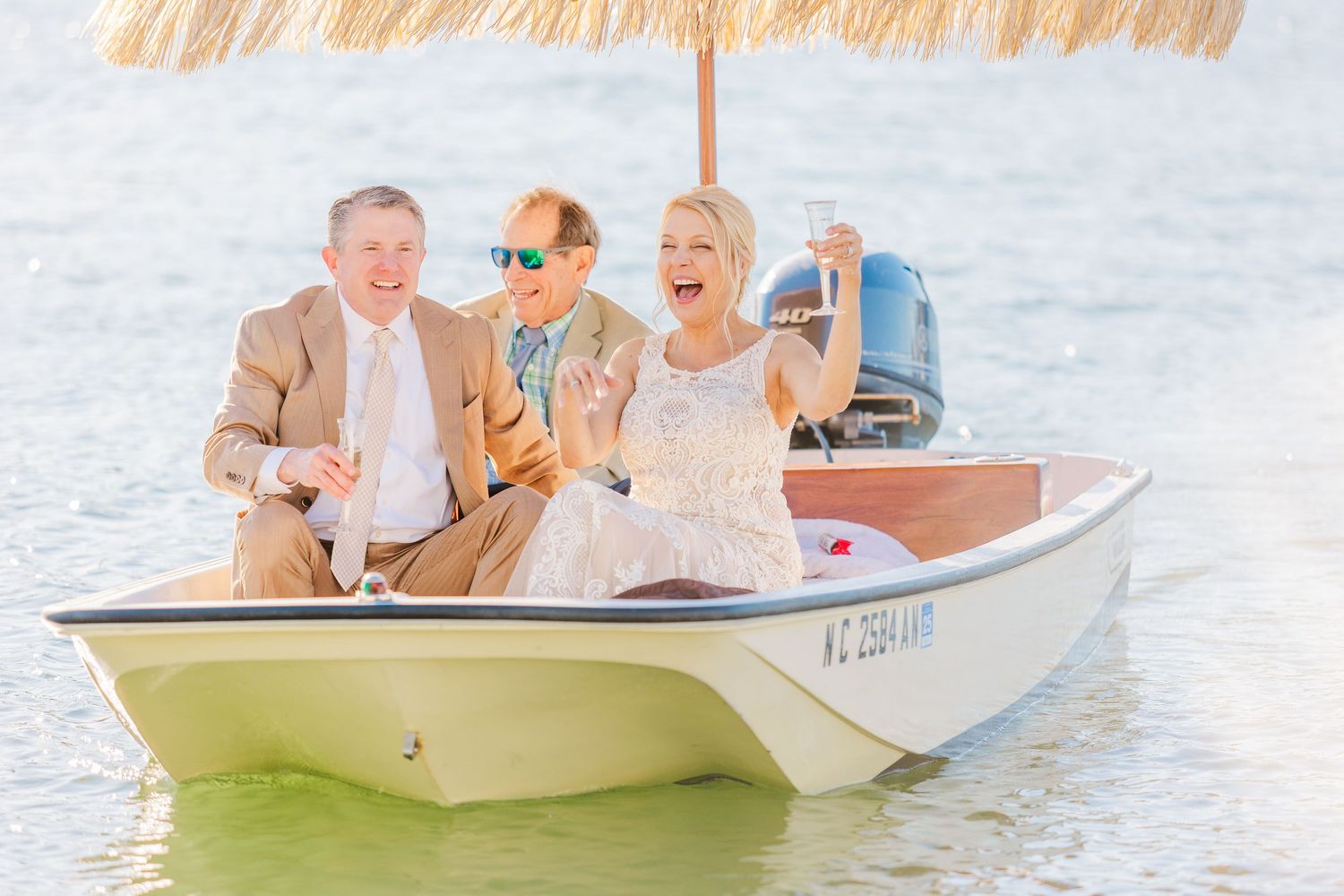 Wedding party enjoying a boat ride on calm waters in a small white vessel.