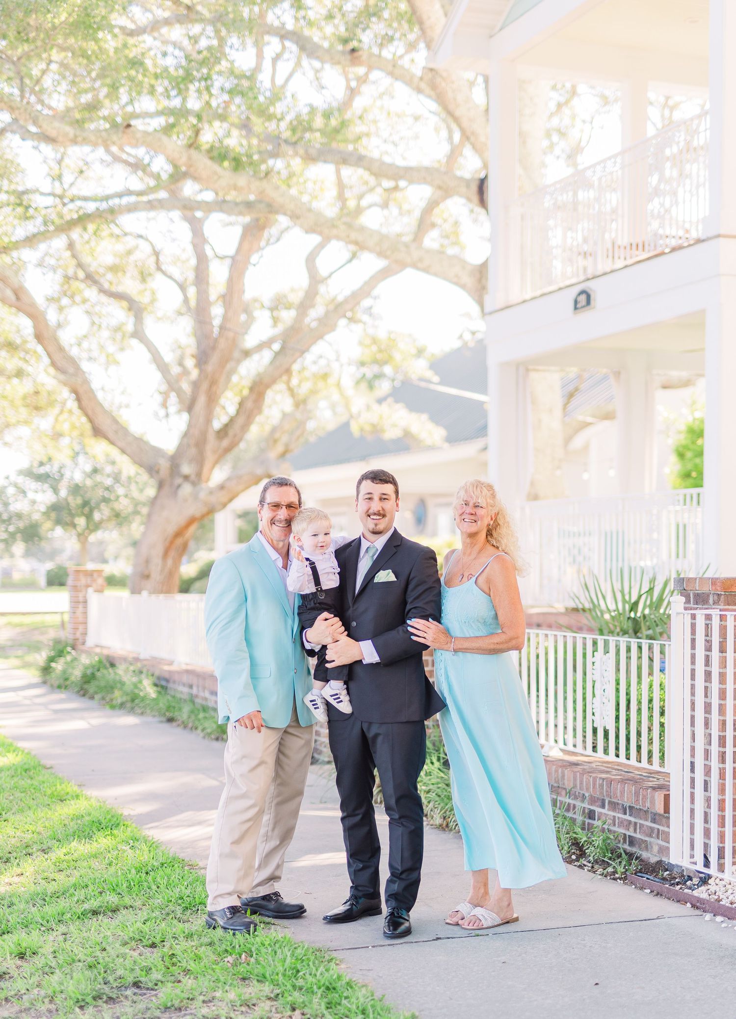 Wedding party poses playfully on a porch with bridesmaids in light blue dresses southport elopement wedding bride groom light and airy class