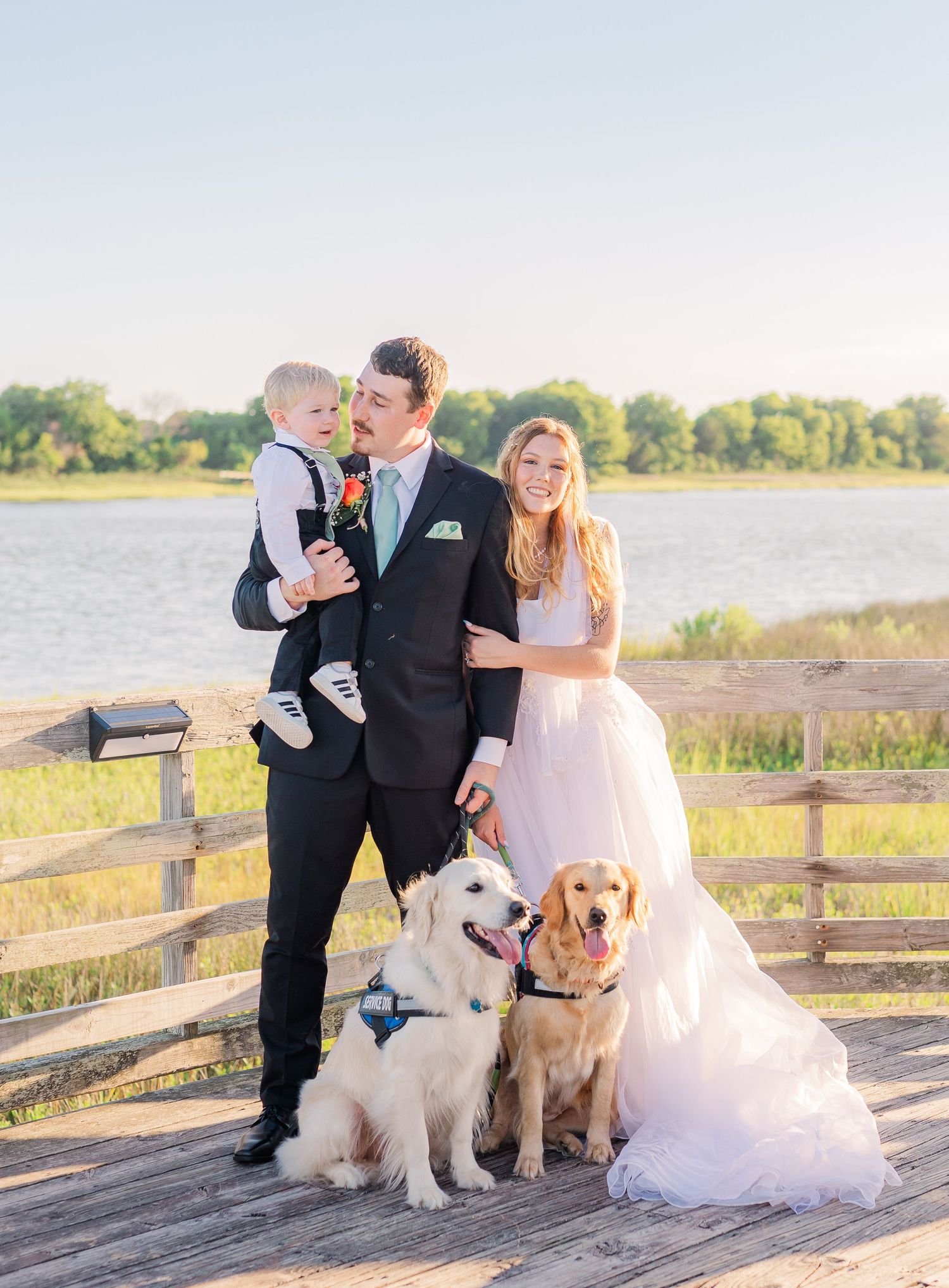 Wedding party poses with their dogs on a wooden boardwalk southport elopement wedding bride groom light and airy classic