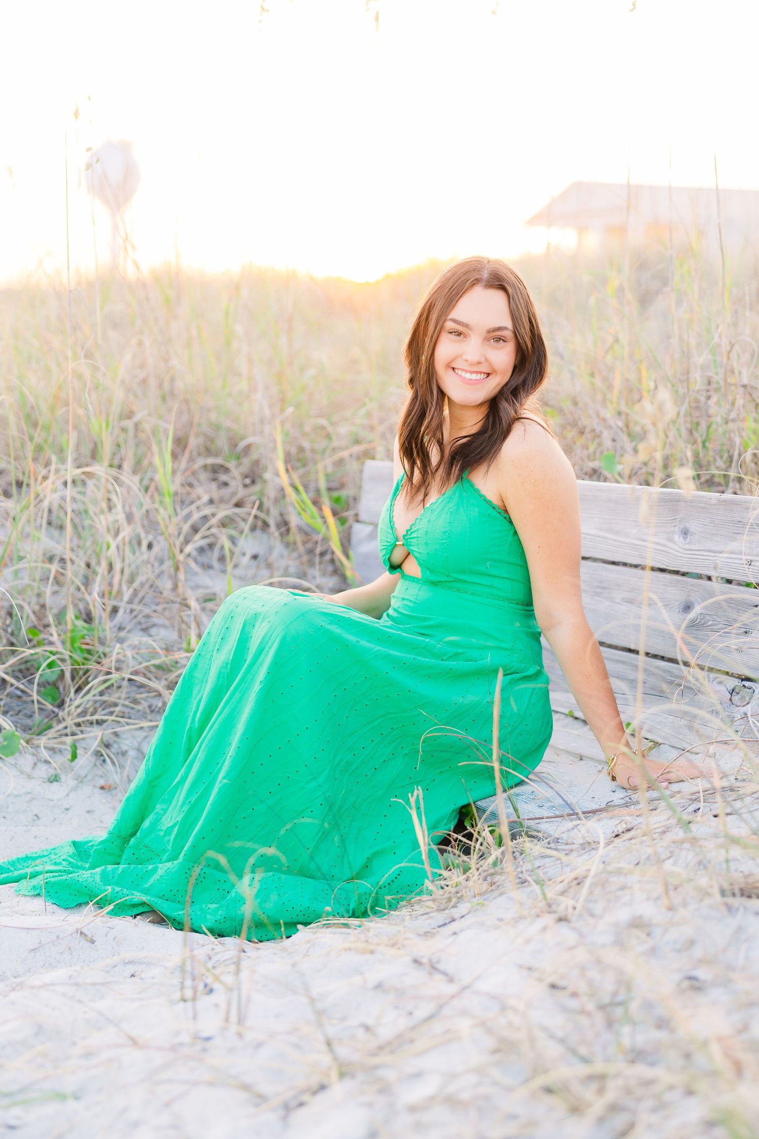 Beachside photo session with a bright green maxi dress among coastal dunes and grass.