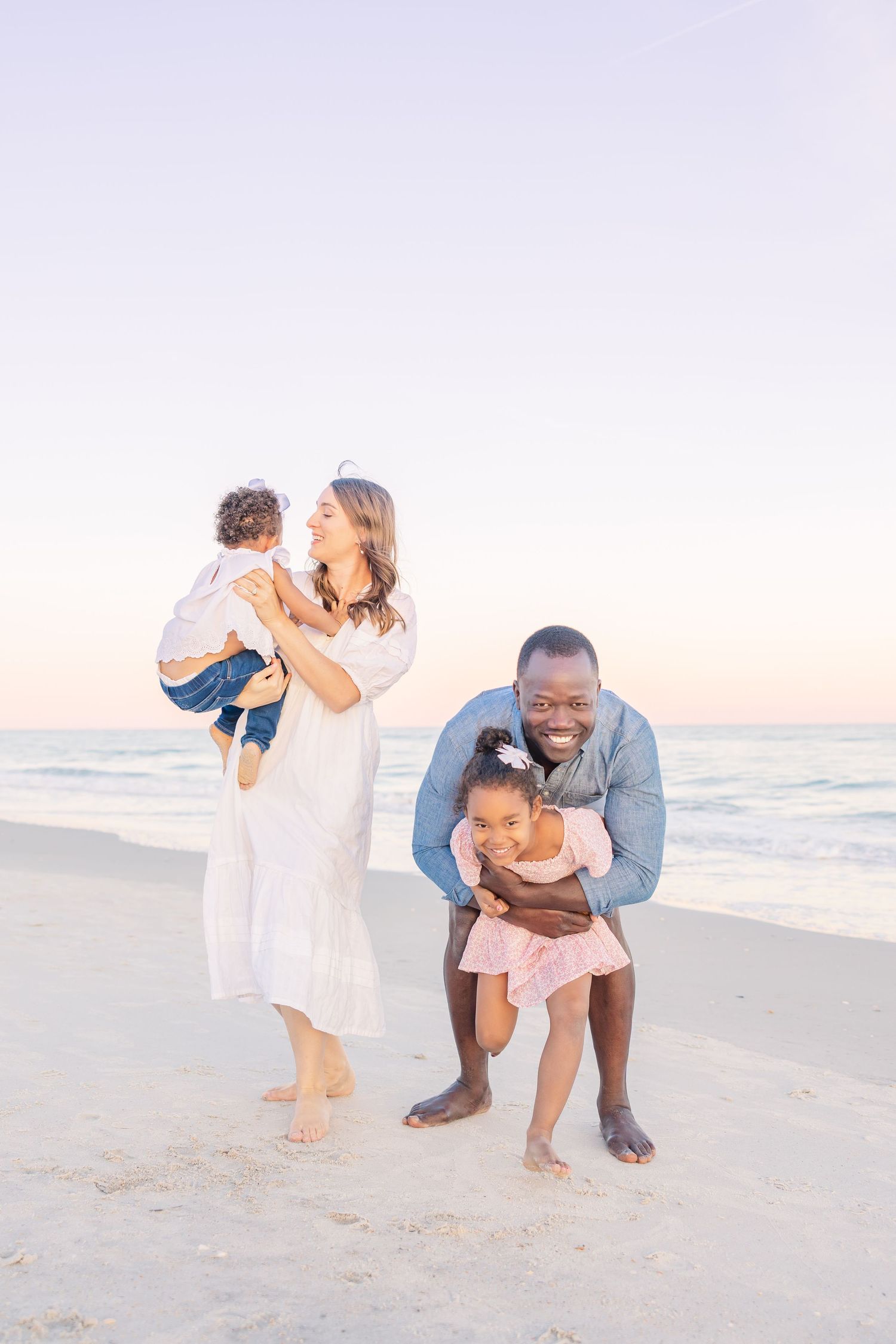 Family enjoying playtime together on beach at sunset.