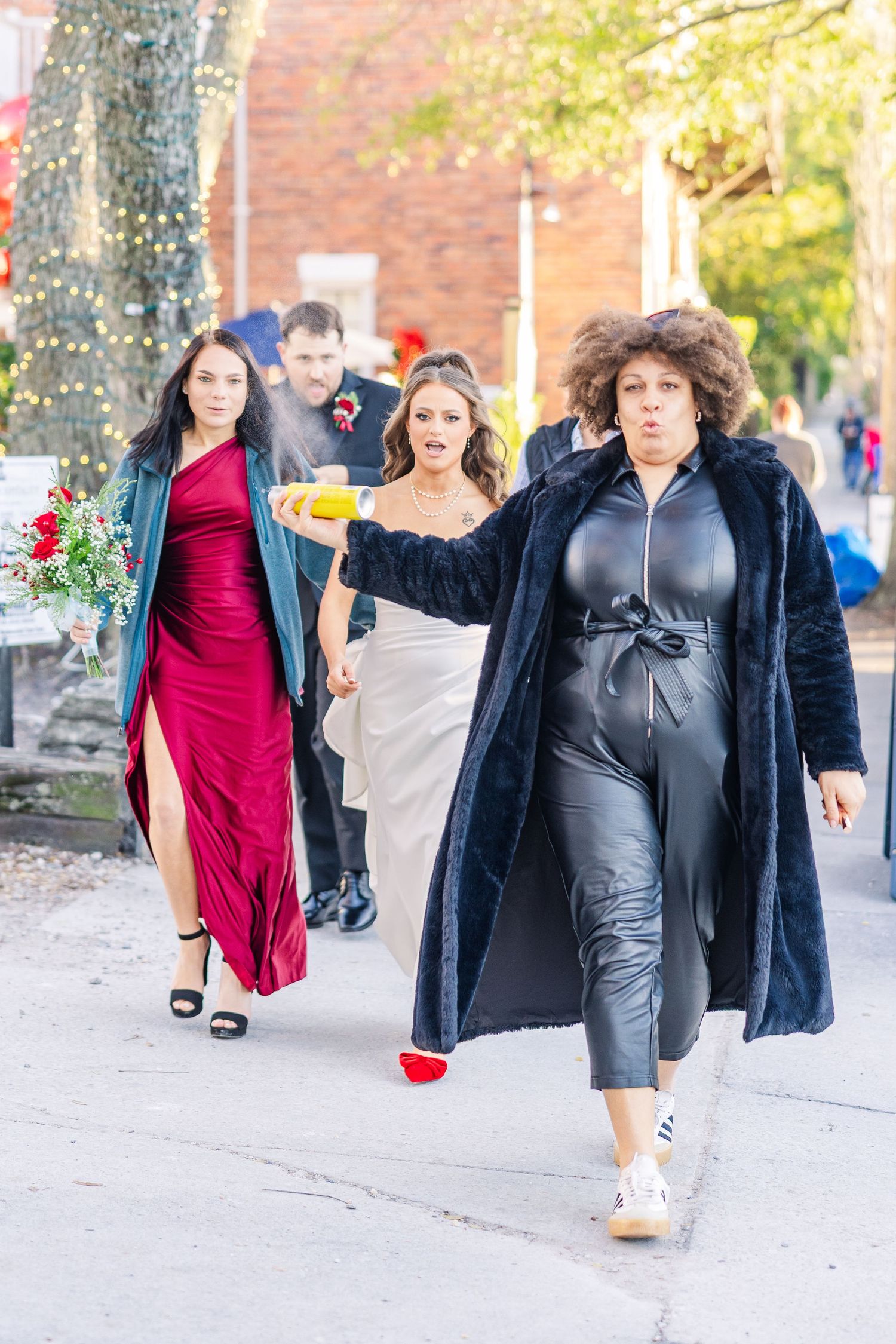 Wedding party walking together on city sidewalk with festive holiday decorations.