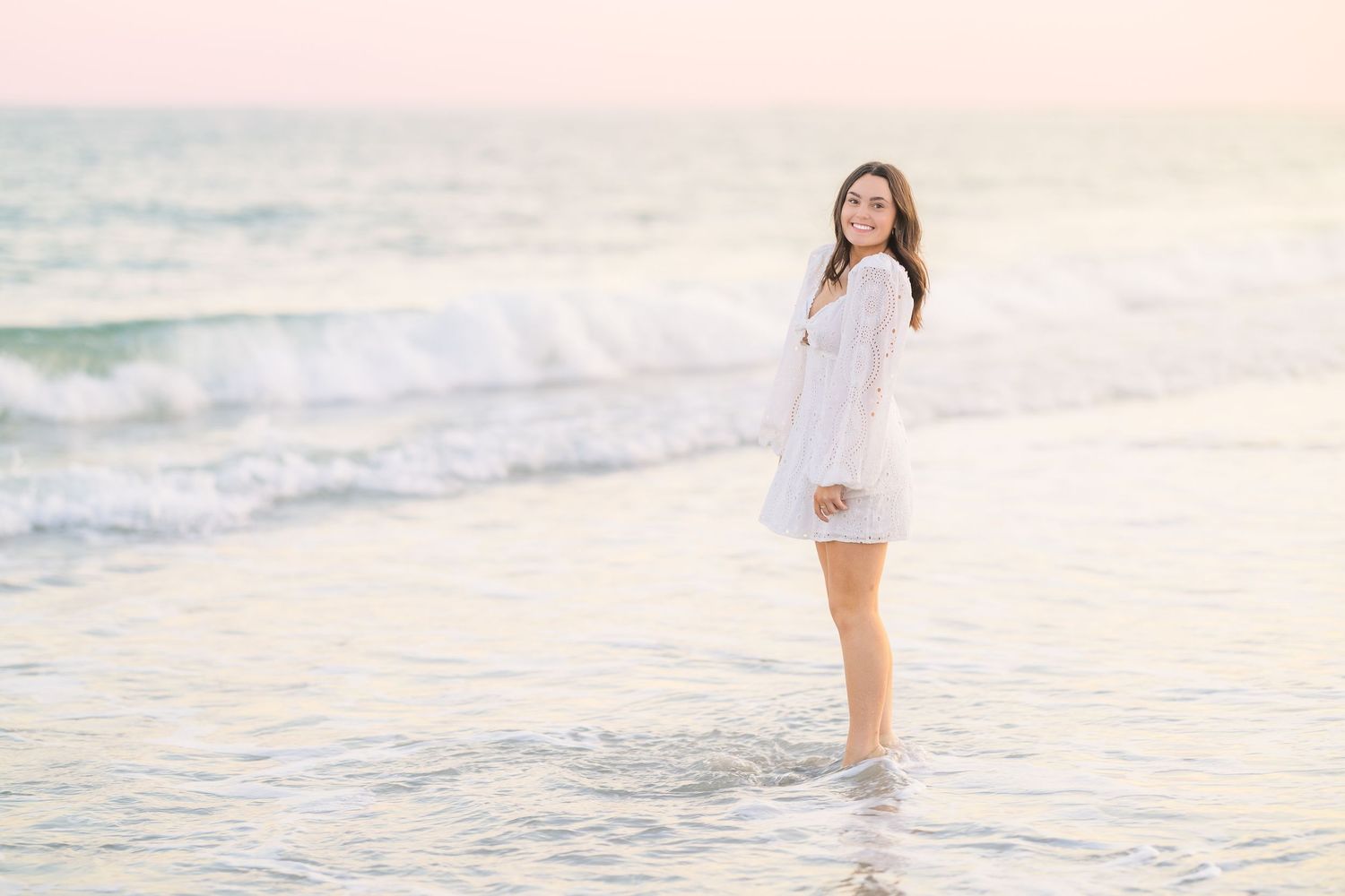 Carefree beach moment captured with waves and soft pink sunset lighting.
