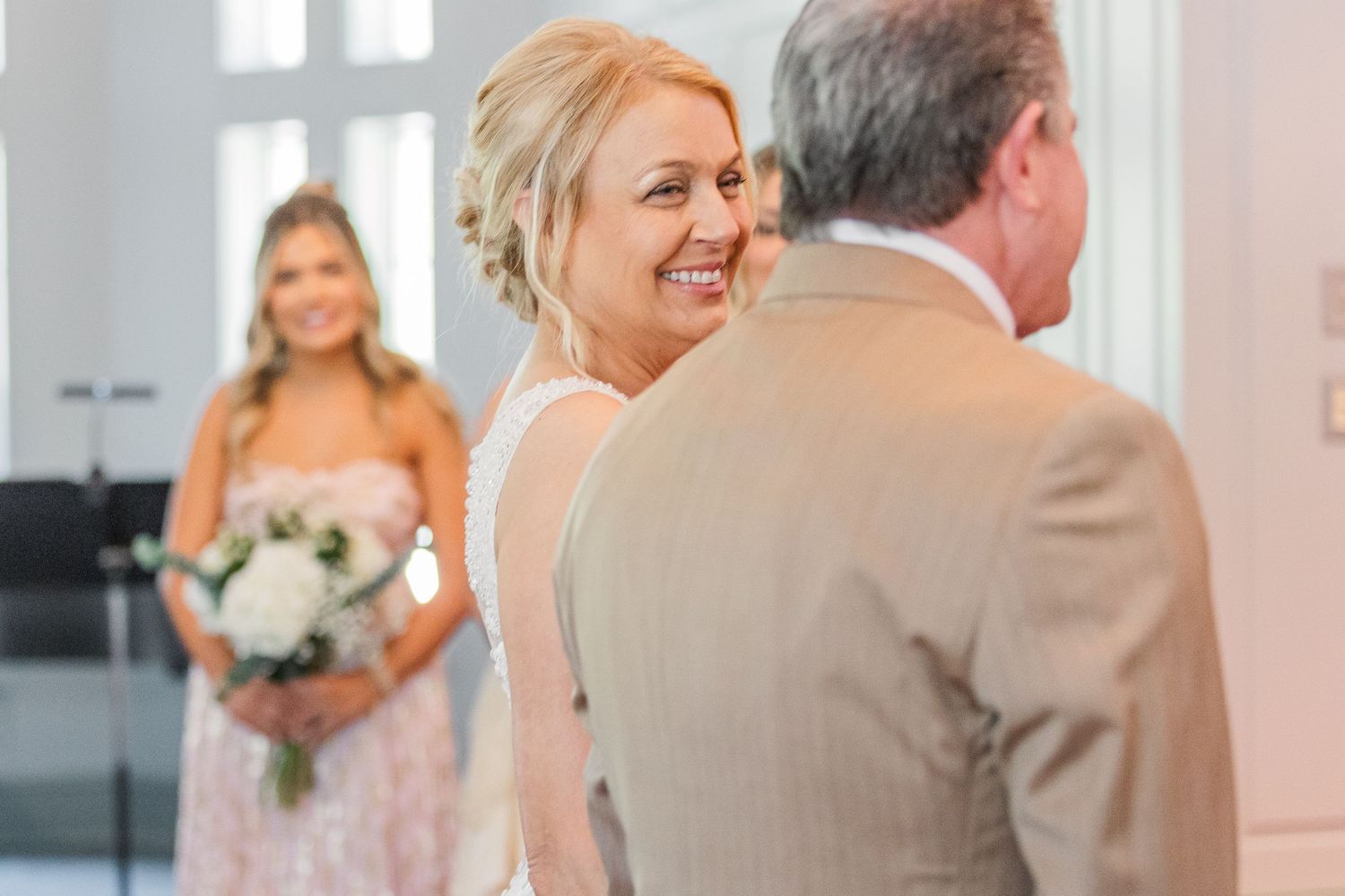Emotional wedding ceremony moment captured in bright white church setting.