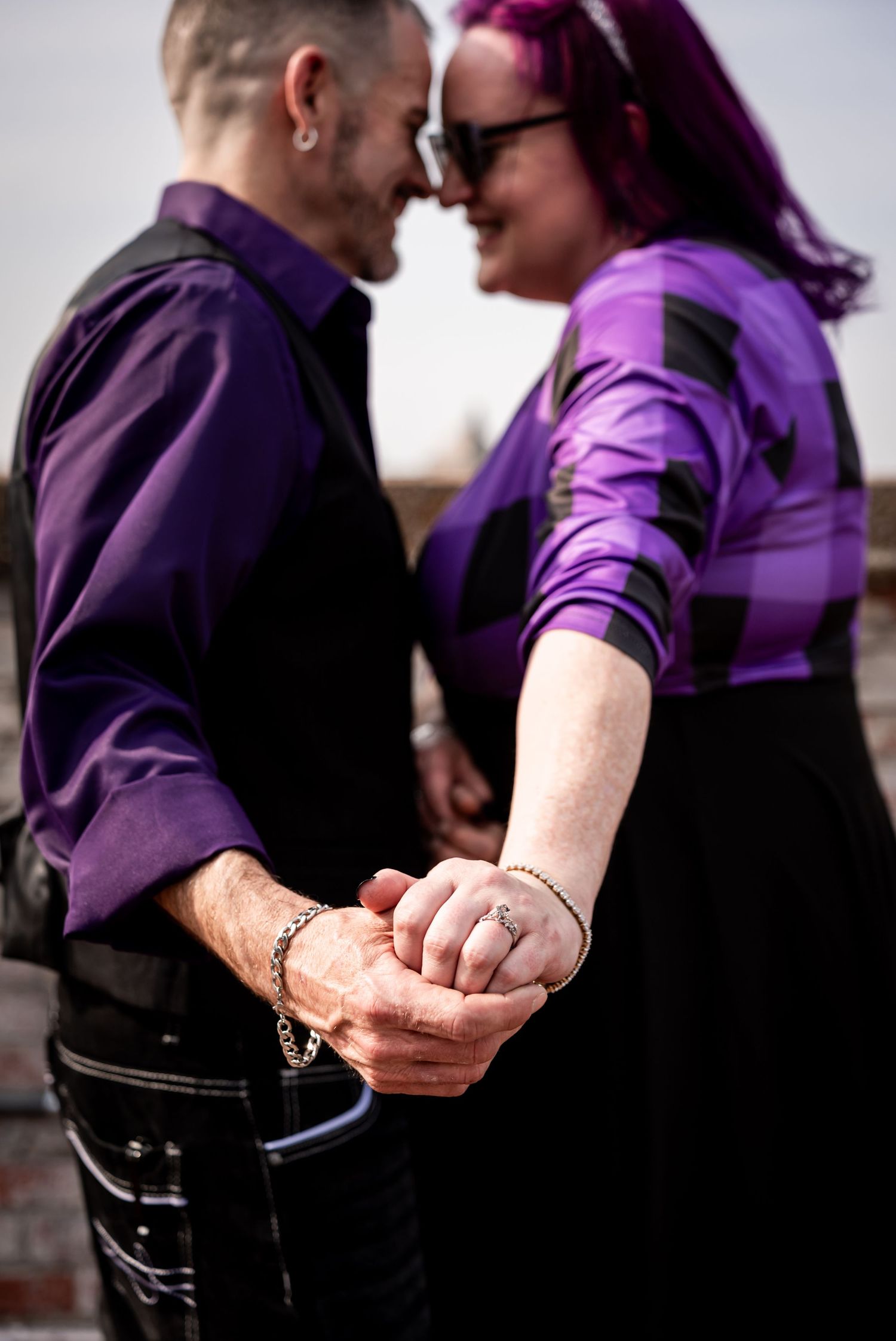 Close-up of a couple holding hands with purple clothing details visible.