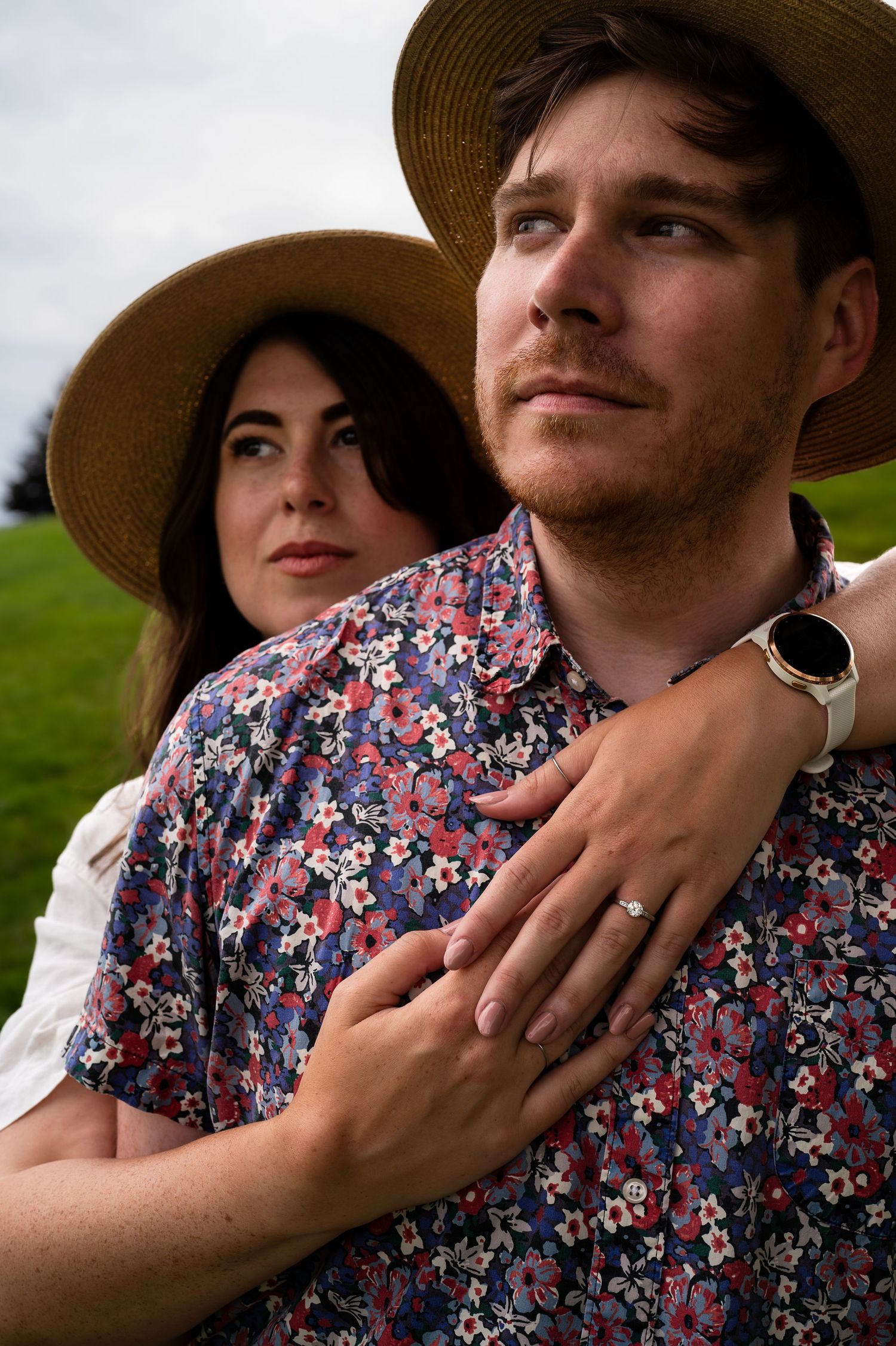 Close-up of a couple wearing straw hats and floral clothing outdoors.