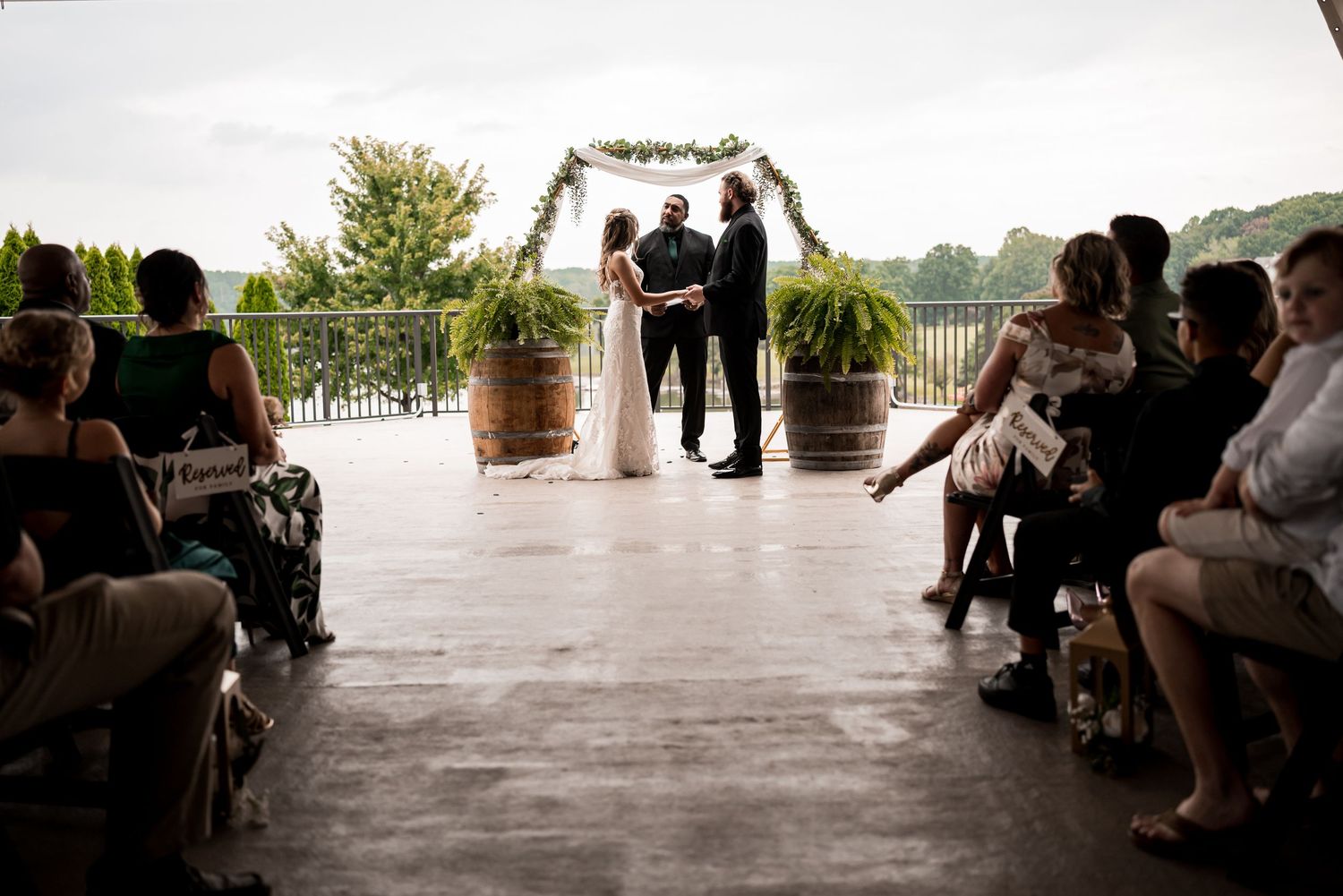 Wedding ceremony setup with guests seated beneath a covered outdoor venue.