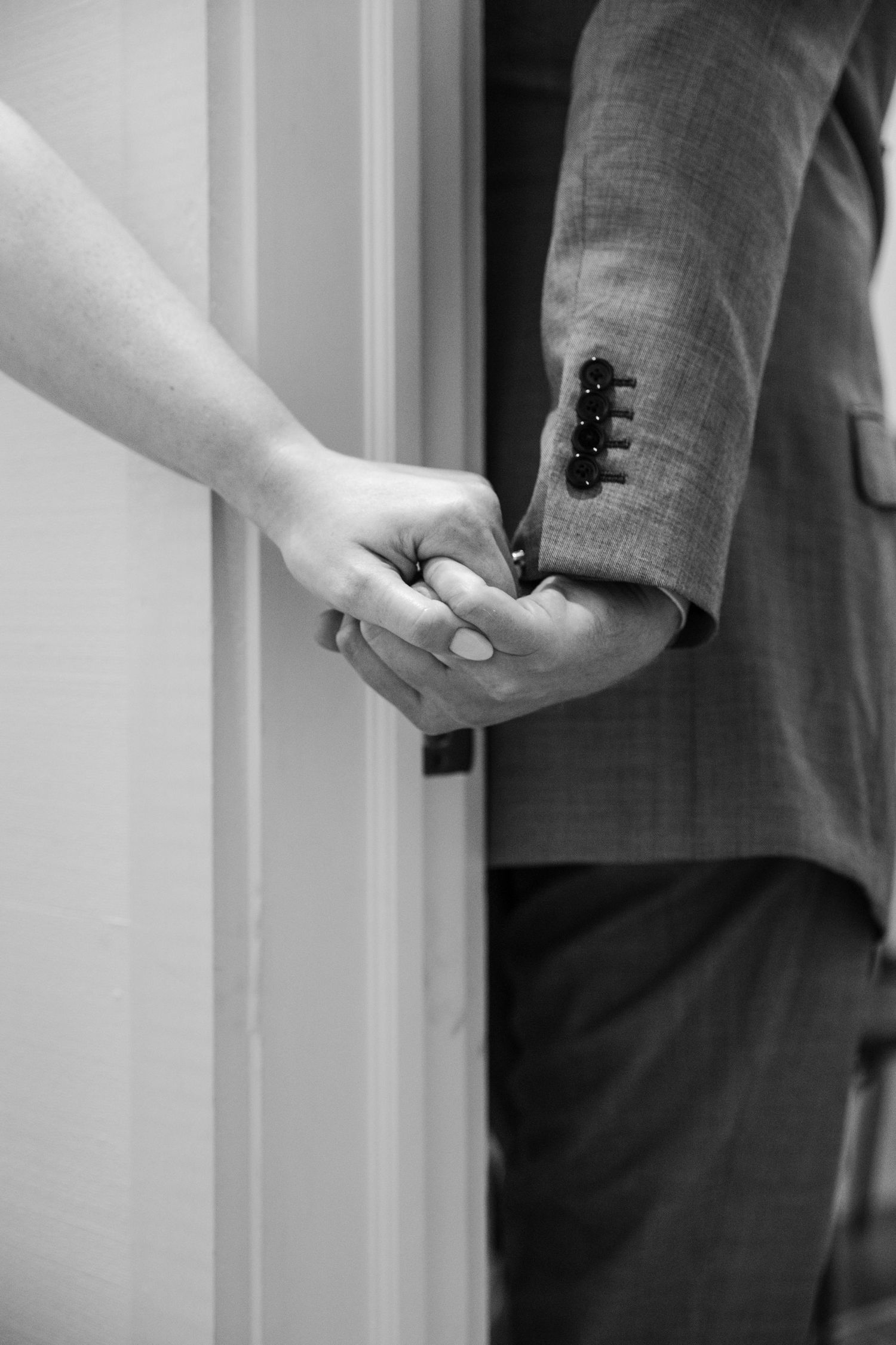 Close-up of a couple holding hands in a doorway.
