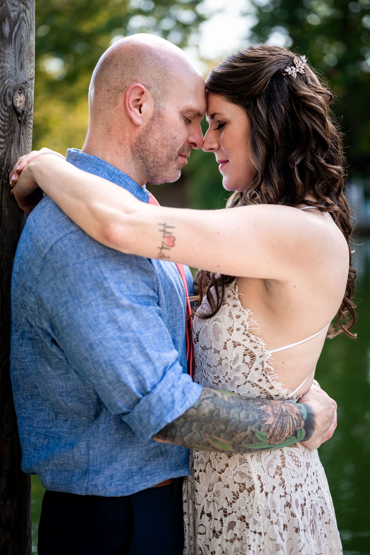 Couple embracing during an outdoor portrait session surrounded by greenery at Smith Mountain Lake in Virginia.