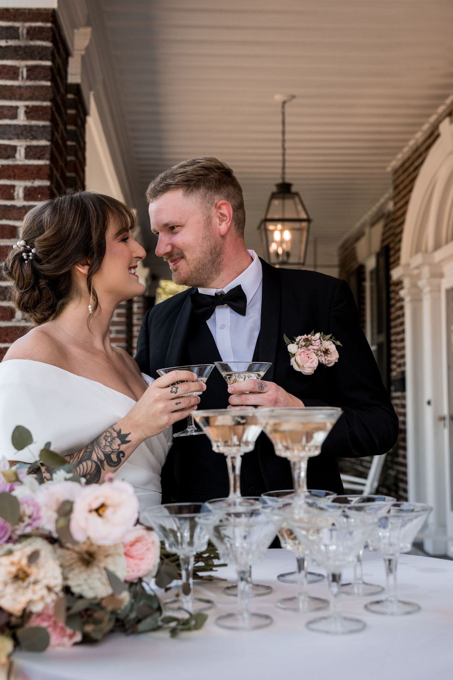 Bride and groom holding cocktails and laughing together at their wedding reception.