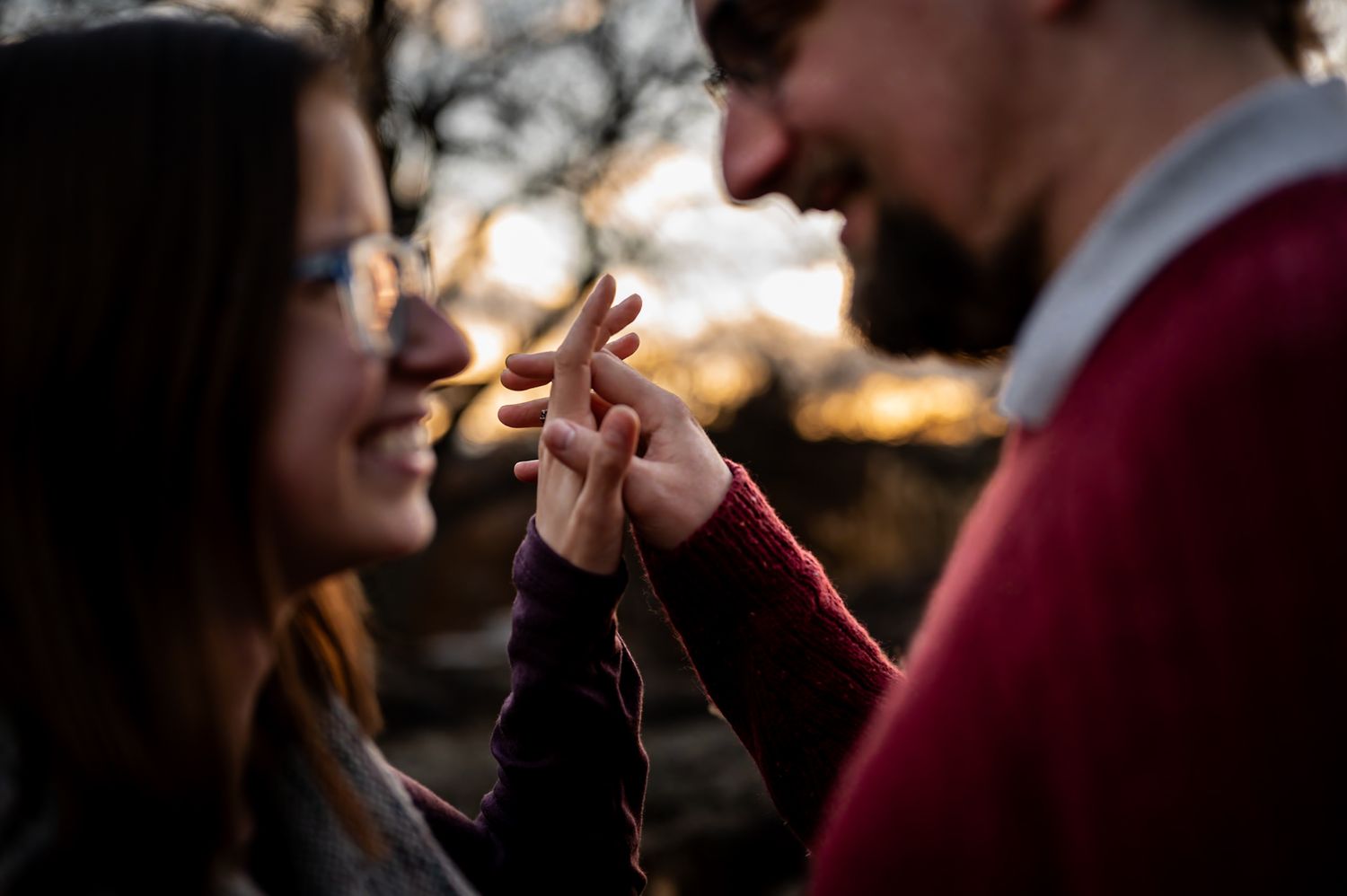 Couple standing close together outdoors during sunset.