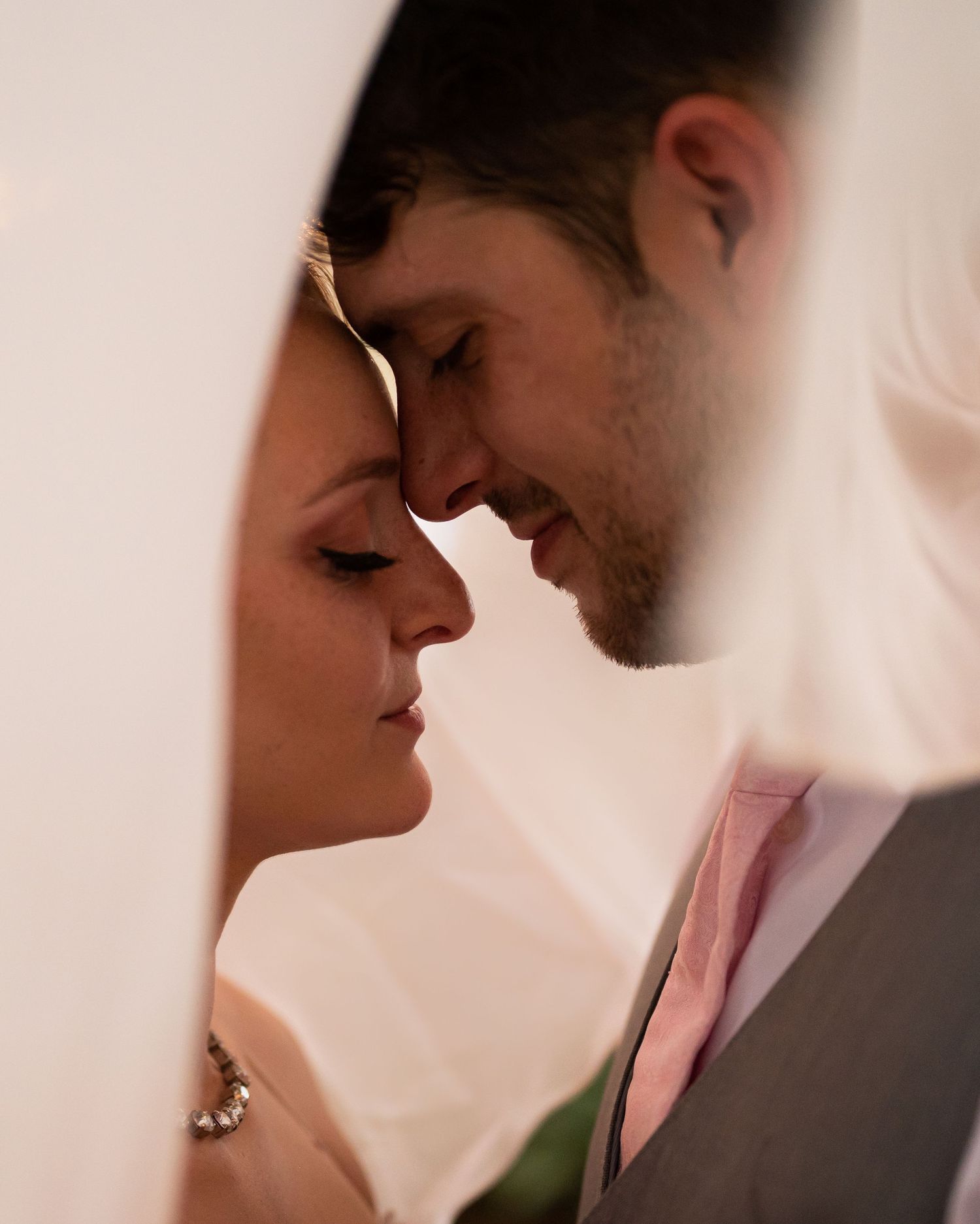 Close-up wedding portrait of couple sharing a quiet moment in soft natural light.