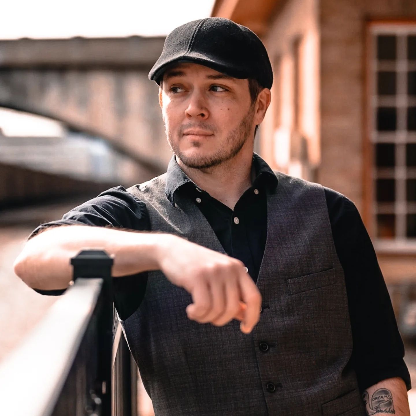 Person wearing a black baseball cap and dark shirt, smiling and looking off to the side.