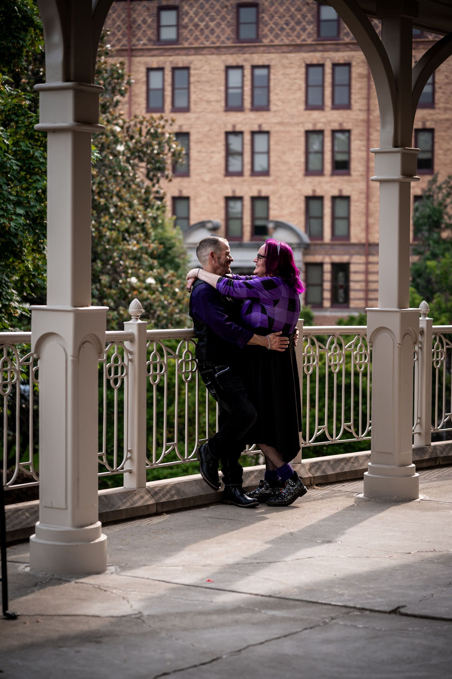Couple in purple attire standing together on a columned porch of a Hotel Roanoke.