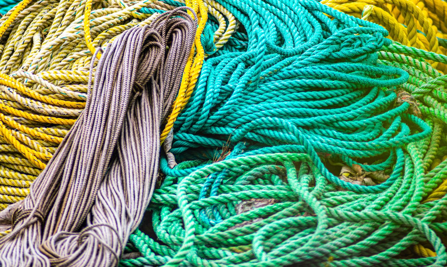 Vibrant twisted ropes in yellow, turquoise, and gray creating a textured pattern.