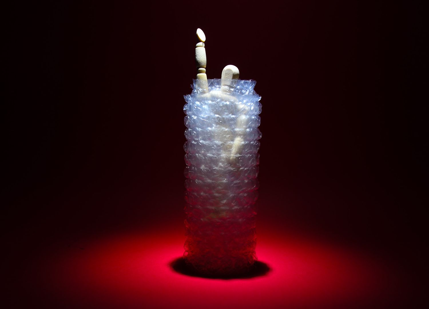 Glowing white LED light sculpture resembling a stacked cylinder against dark background with red accent lighting.