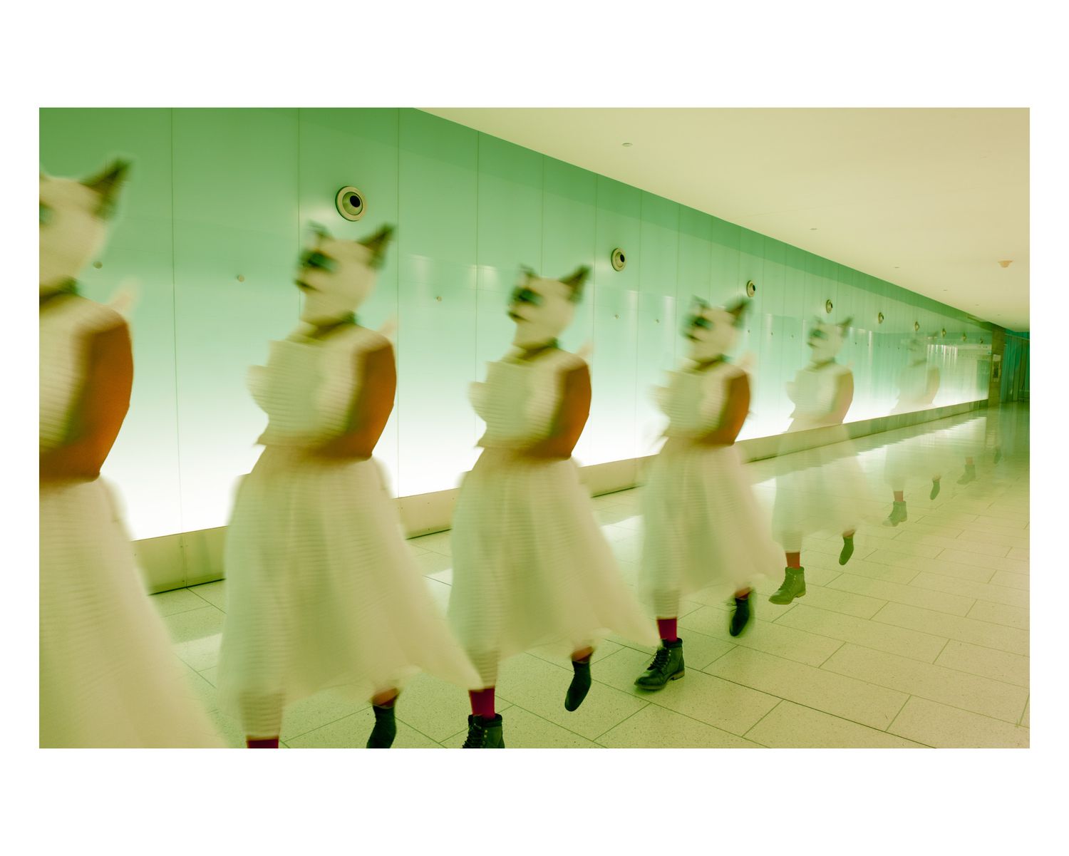 A row of illuminated white mannequins displayed in a minimalist green-tinted hallway.