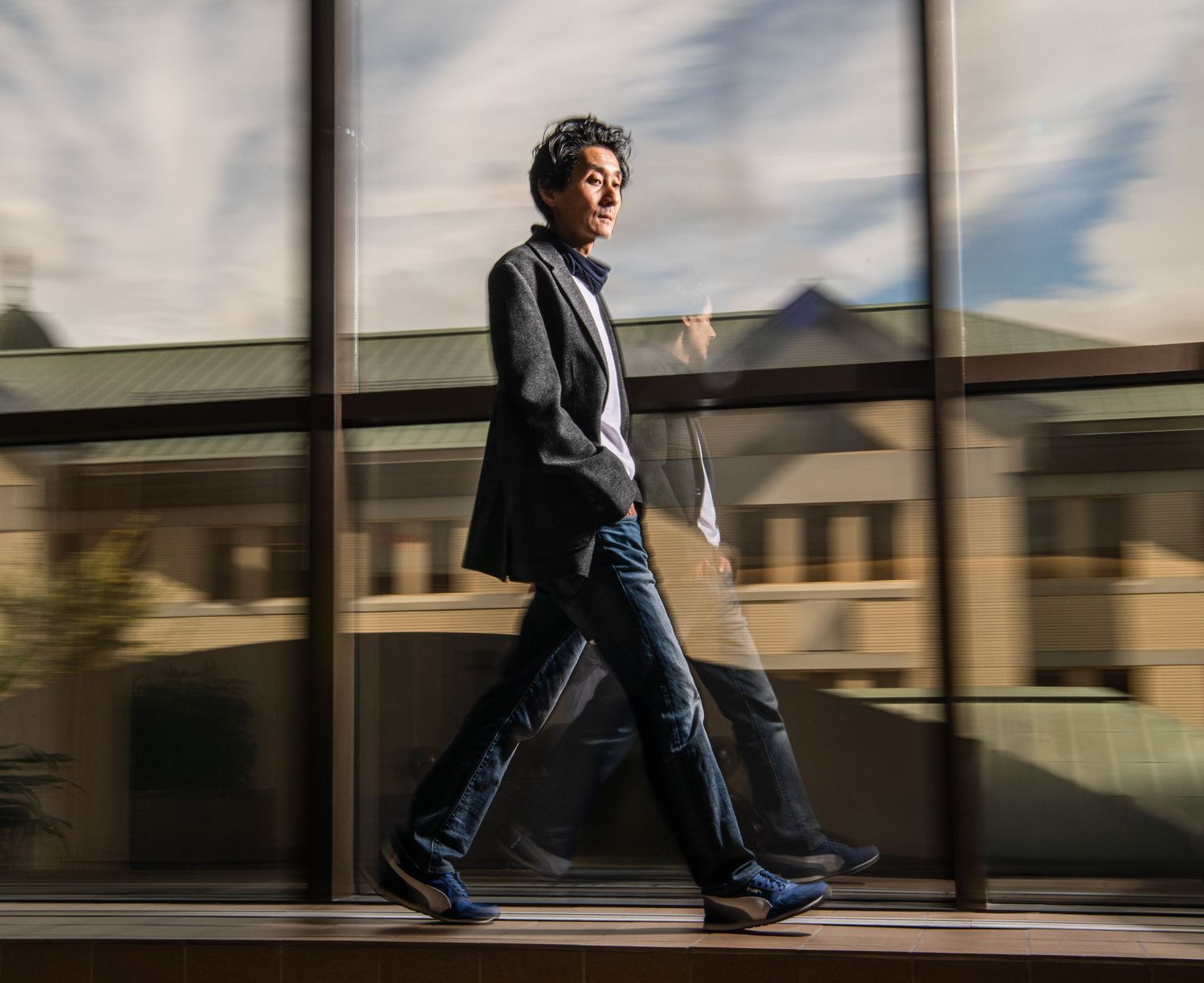 Person walking past reflective windows in motion blur effect.