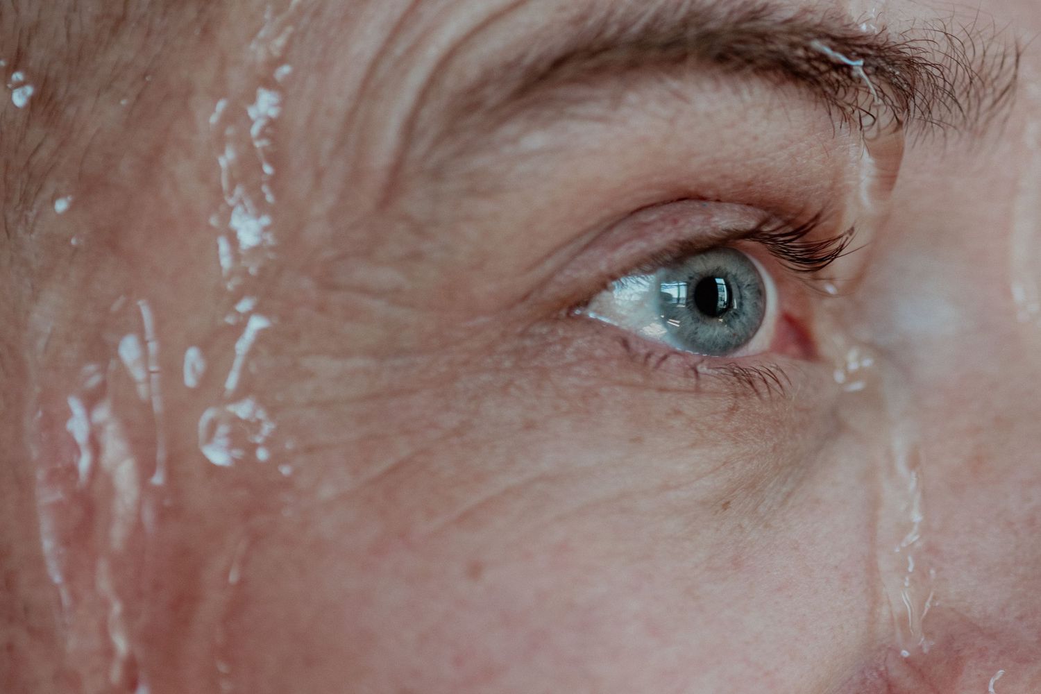 Extreme close-up of blue eye with visible eyelashes and skin texture.