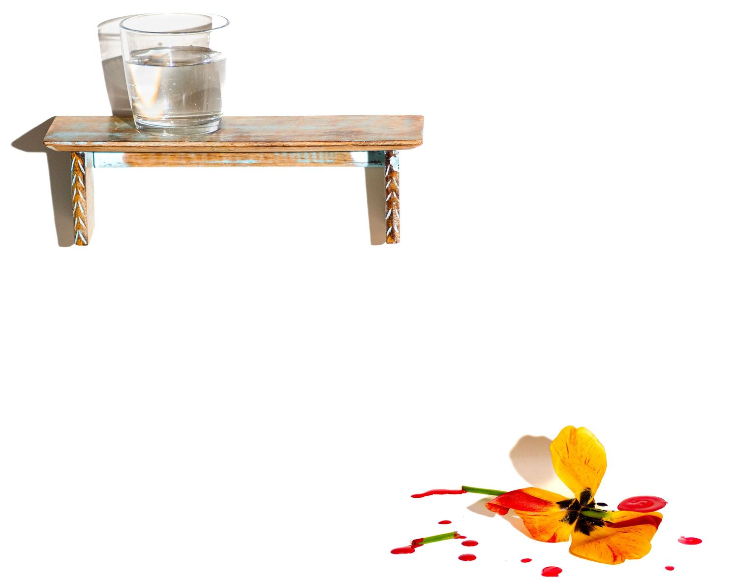 Minimalist wooden shelf display with orange fruit and red splatter artistic elements.