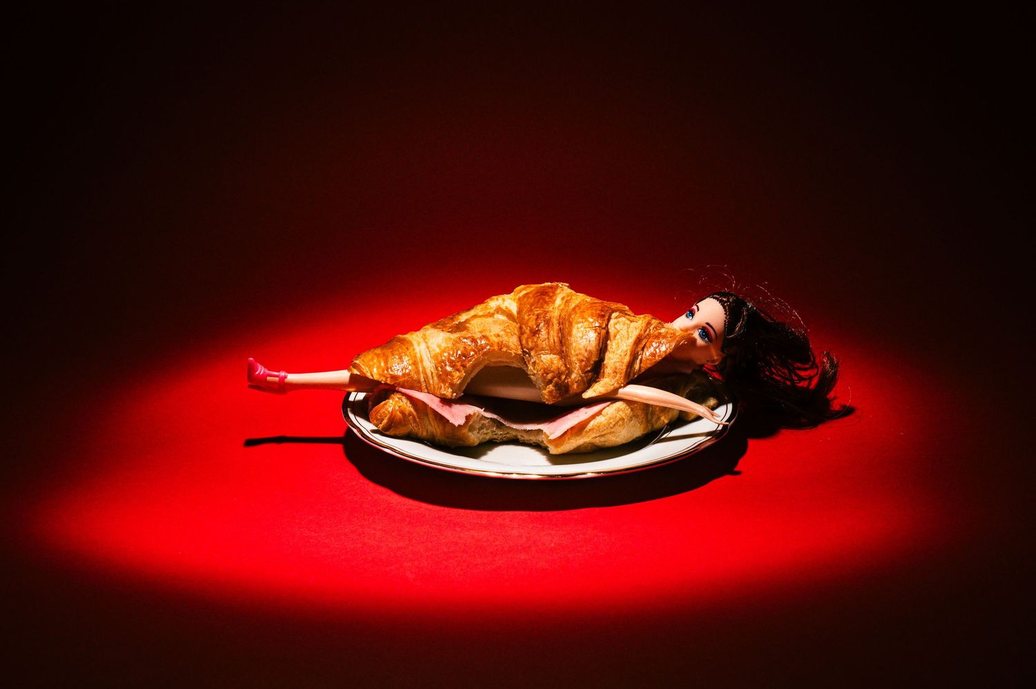 Dramatic low-key lighting on figure lying across dark surface with red glow.