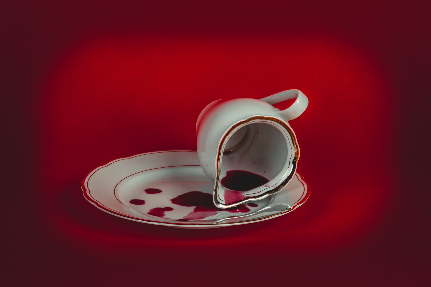 White teacup and saucer casting dramatic shadows against deep red background.