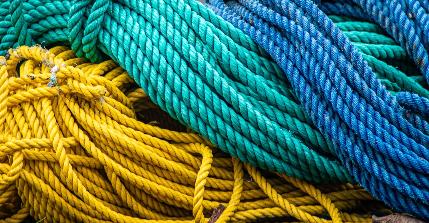 Colorful nautical ropes in turquoise, yellow and blue arranged in coiled patterns.