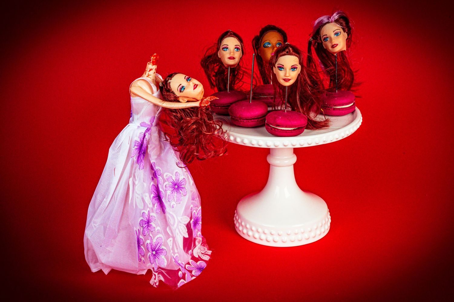Collection of dolls arranged around white teacups on red background in artistic composition.