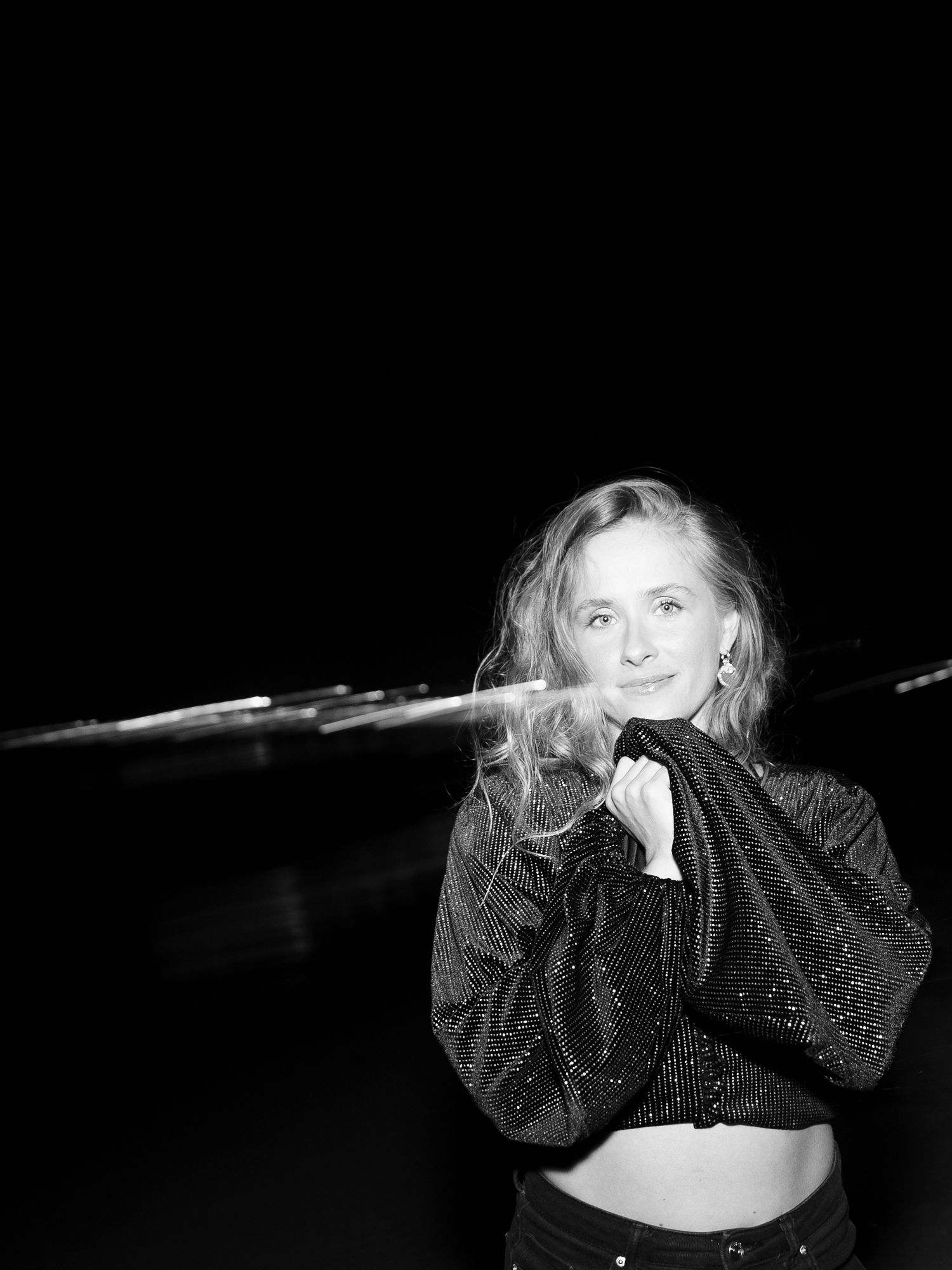 Artistic black and white portrait with sparkly dark clothing against dark background.