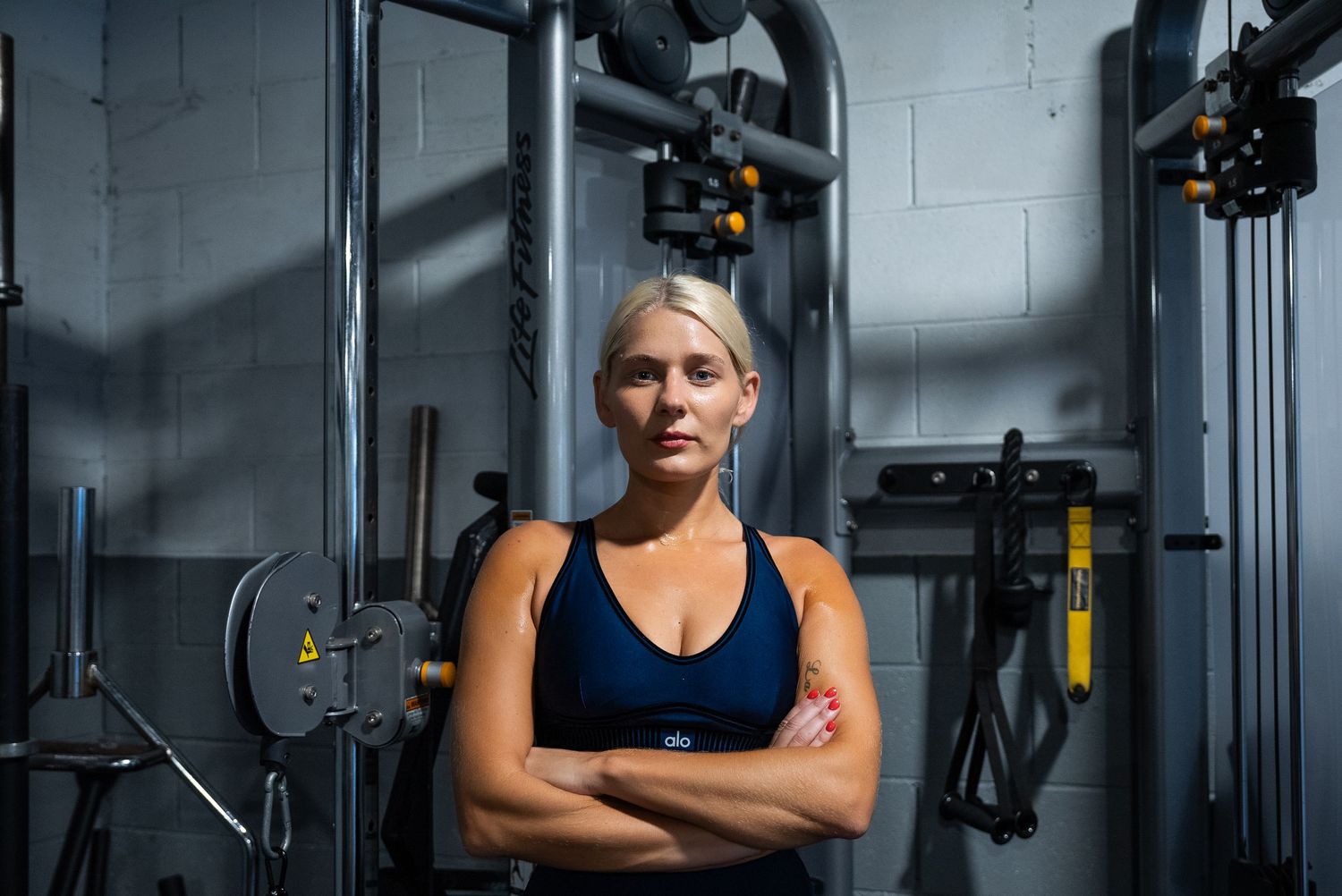 Dramatic portrait in dimly lit gym with exercise equipment.