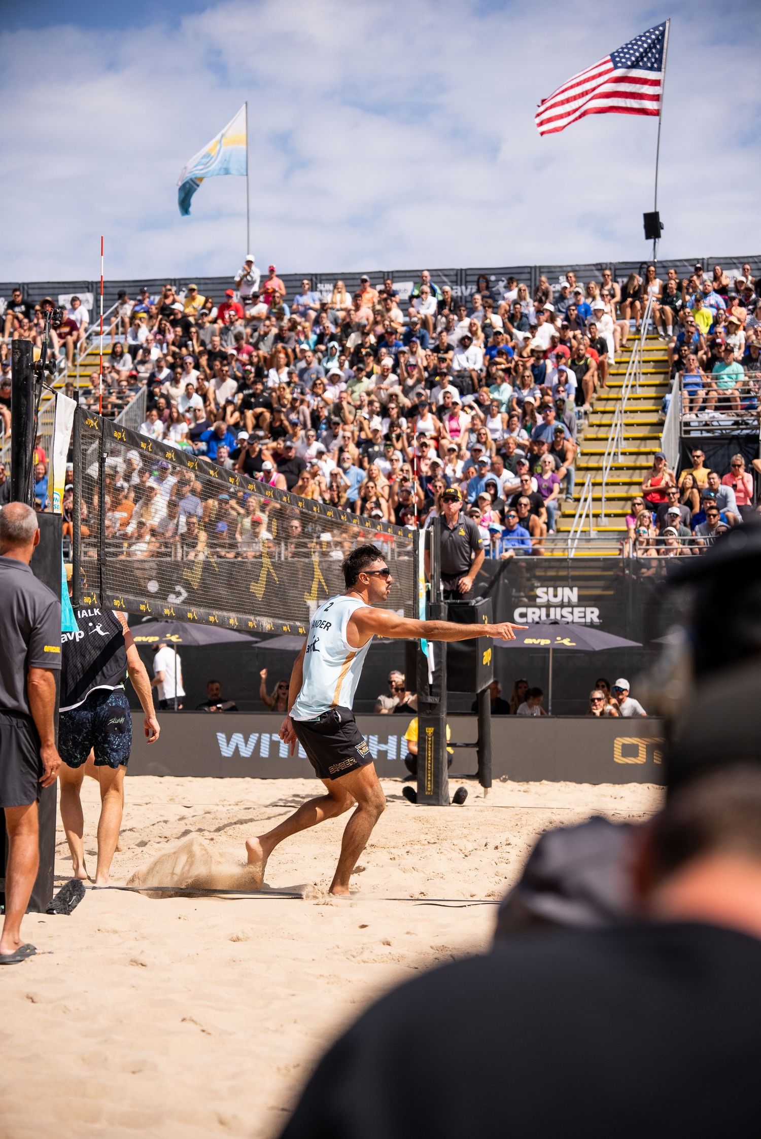 Professional beach volleyball tournament with large crowd and American flag.