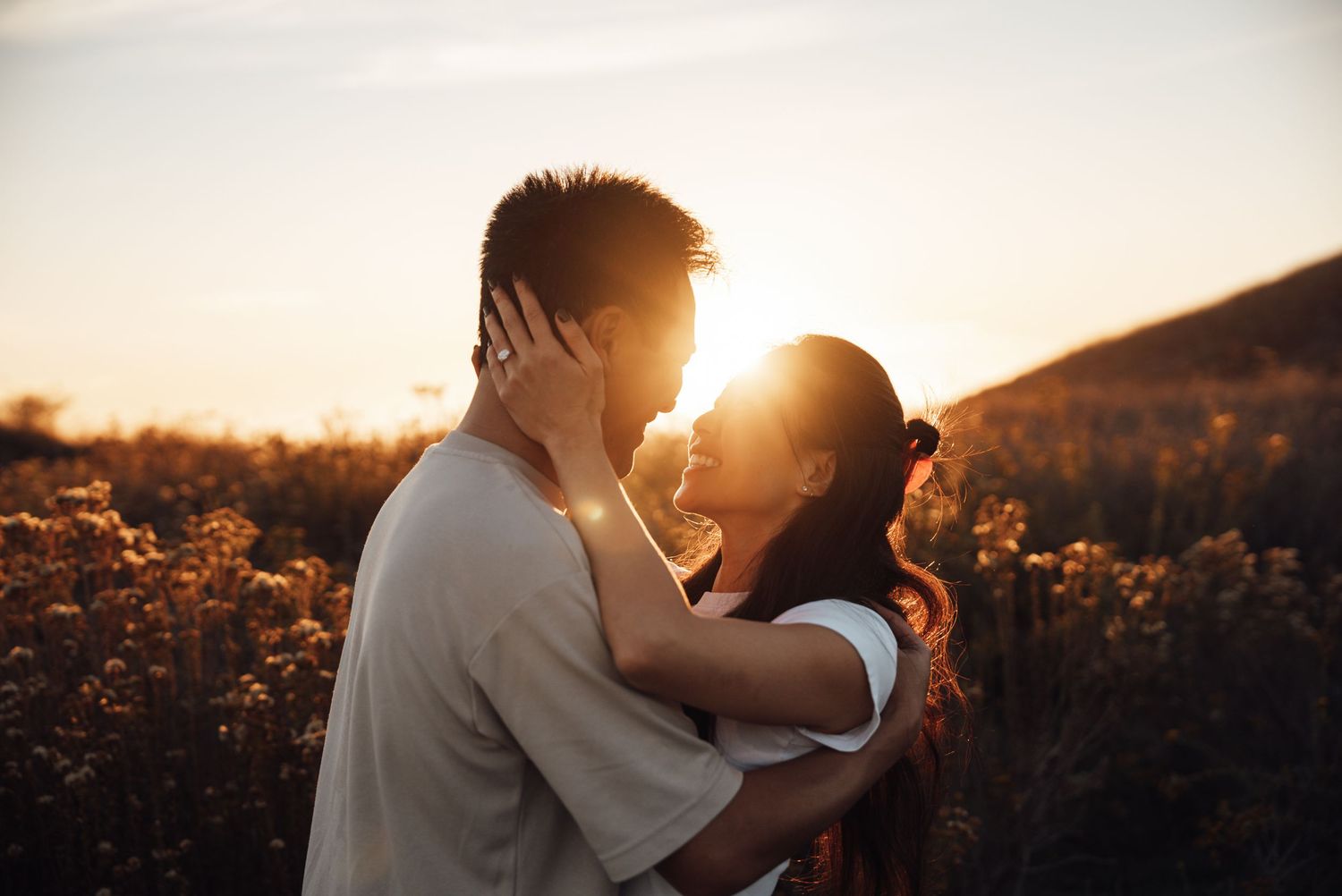 Romantic silhouette of couple embracing at sunset in nature.