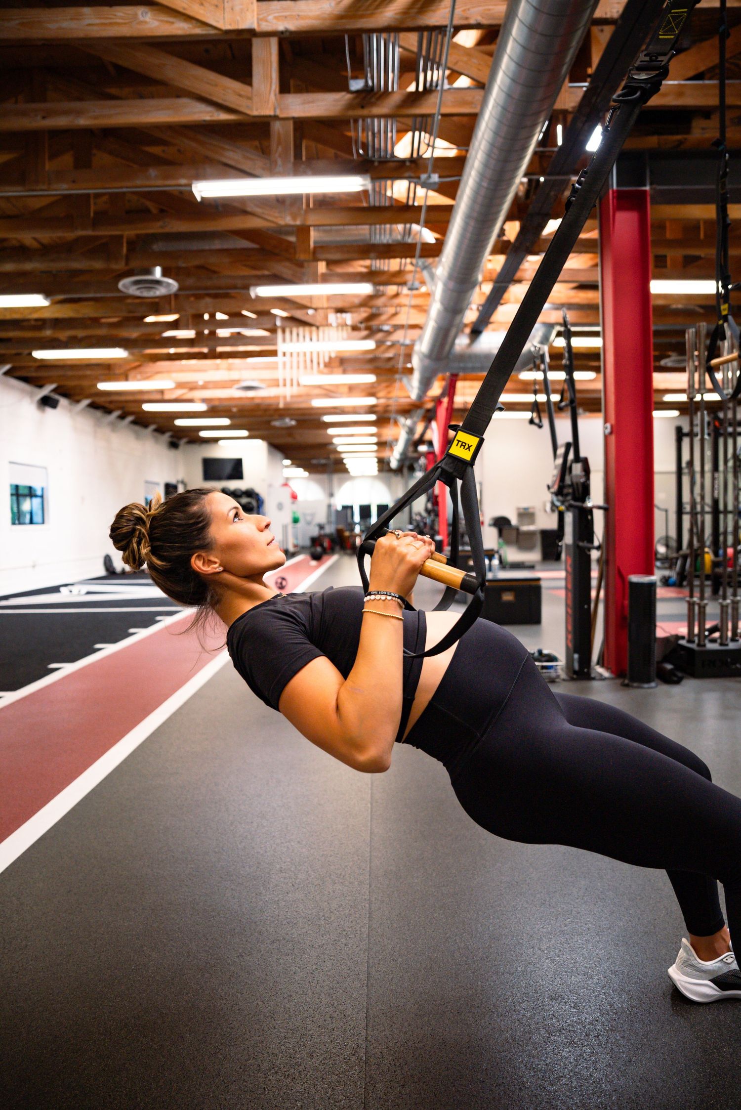 Fitness enthusiast performing suspended bodyweight exercises using TRX straps in a gym.