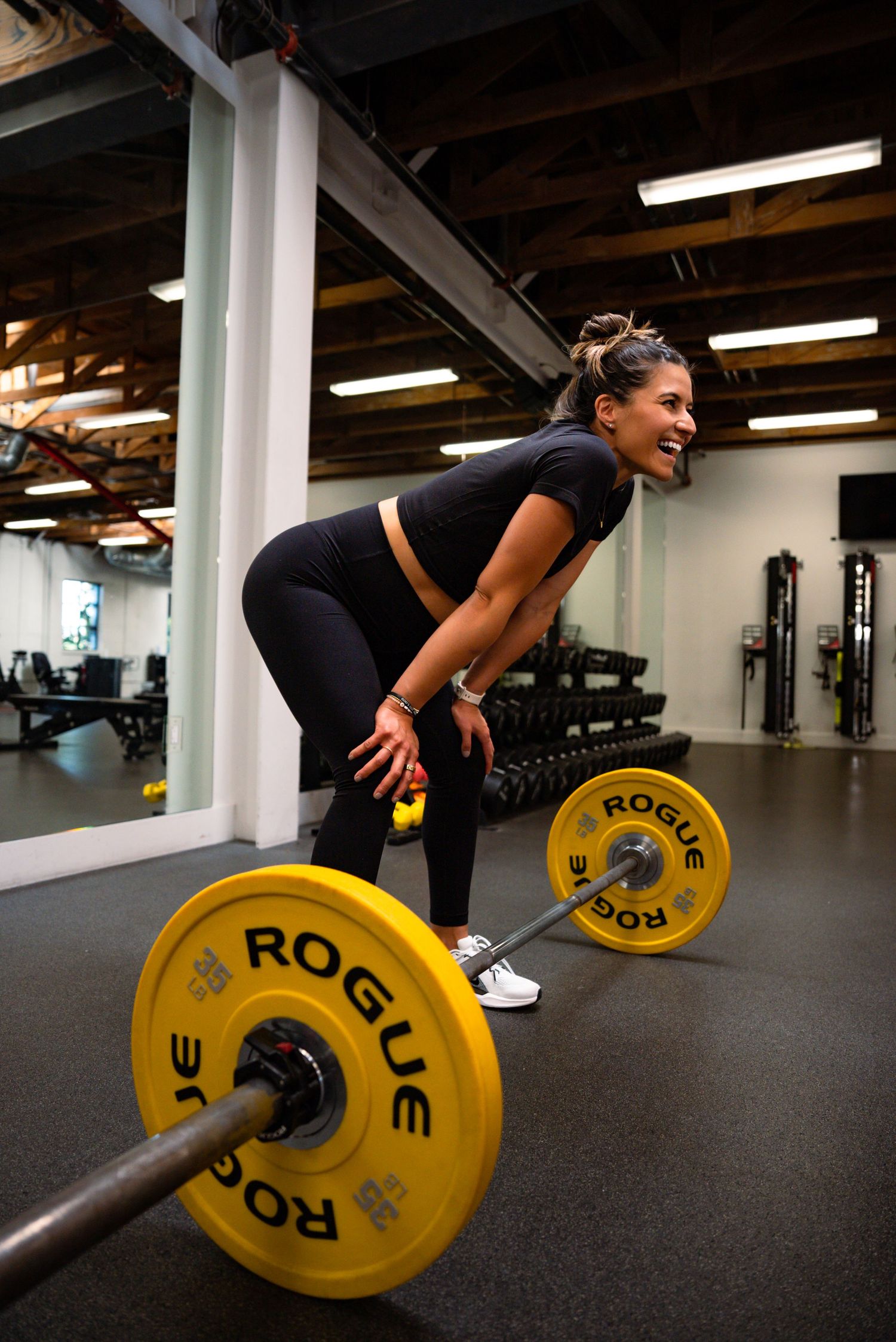 Person demonstrating proper form during barbell deadlift exercise in a fitness facility.