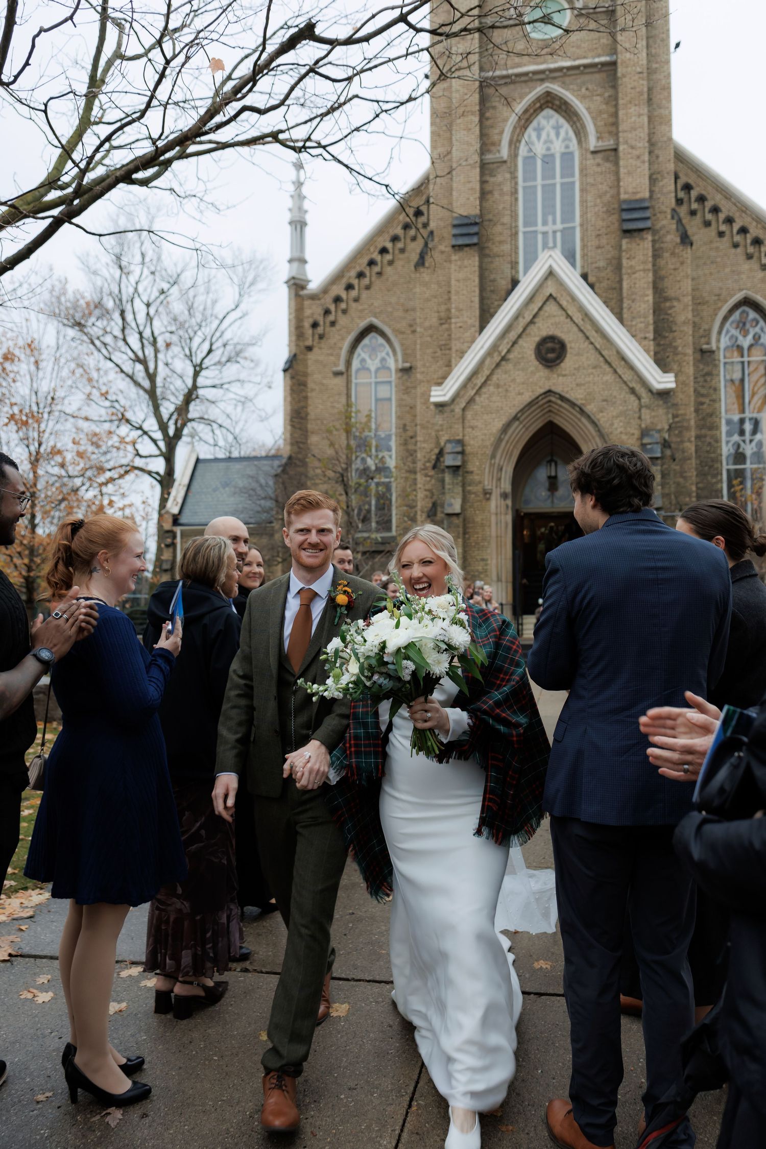 Wedding guests gather outside historic brick church after ceremony.