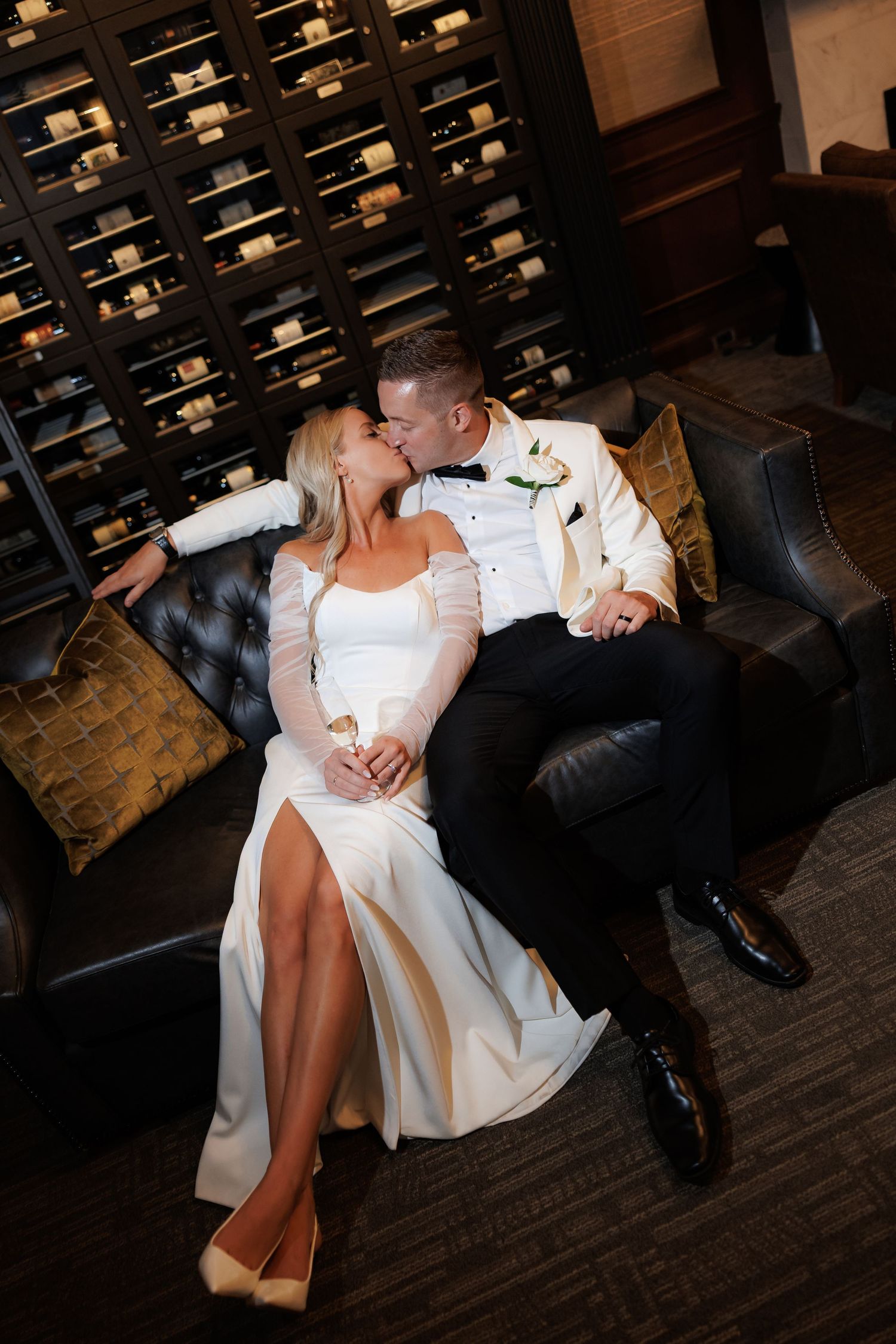 Romantic couple relaxes on dark hardwood floor in elegant wine cellar setting.