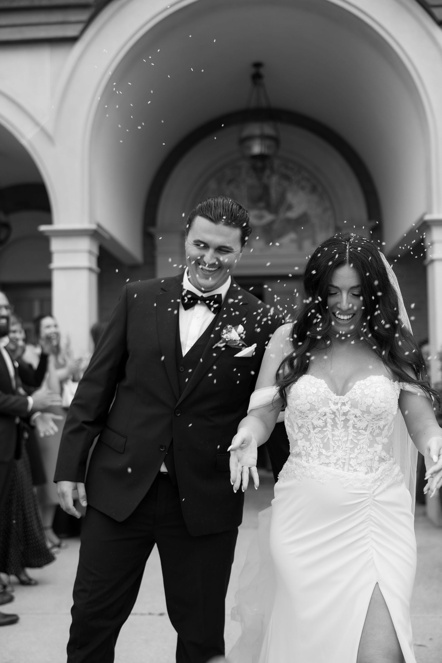 Joyful wedding celebration with confetti shower under church archway.
