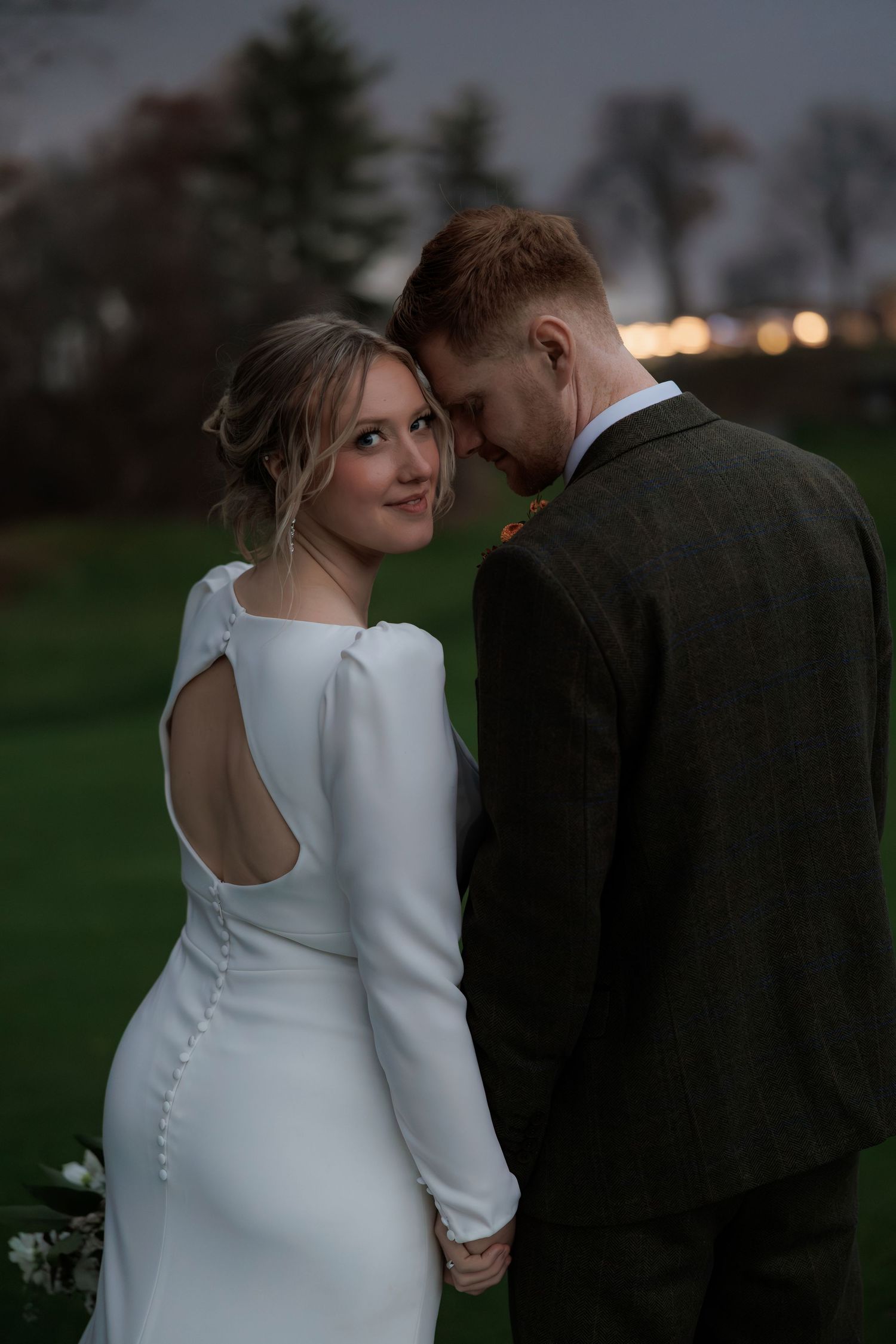 Intimate wedding portraits of a couple in white dress and dark suit at dusk.