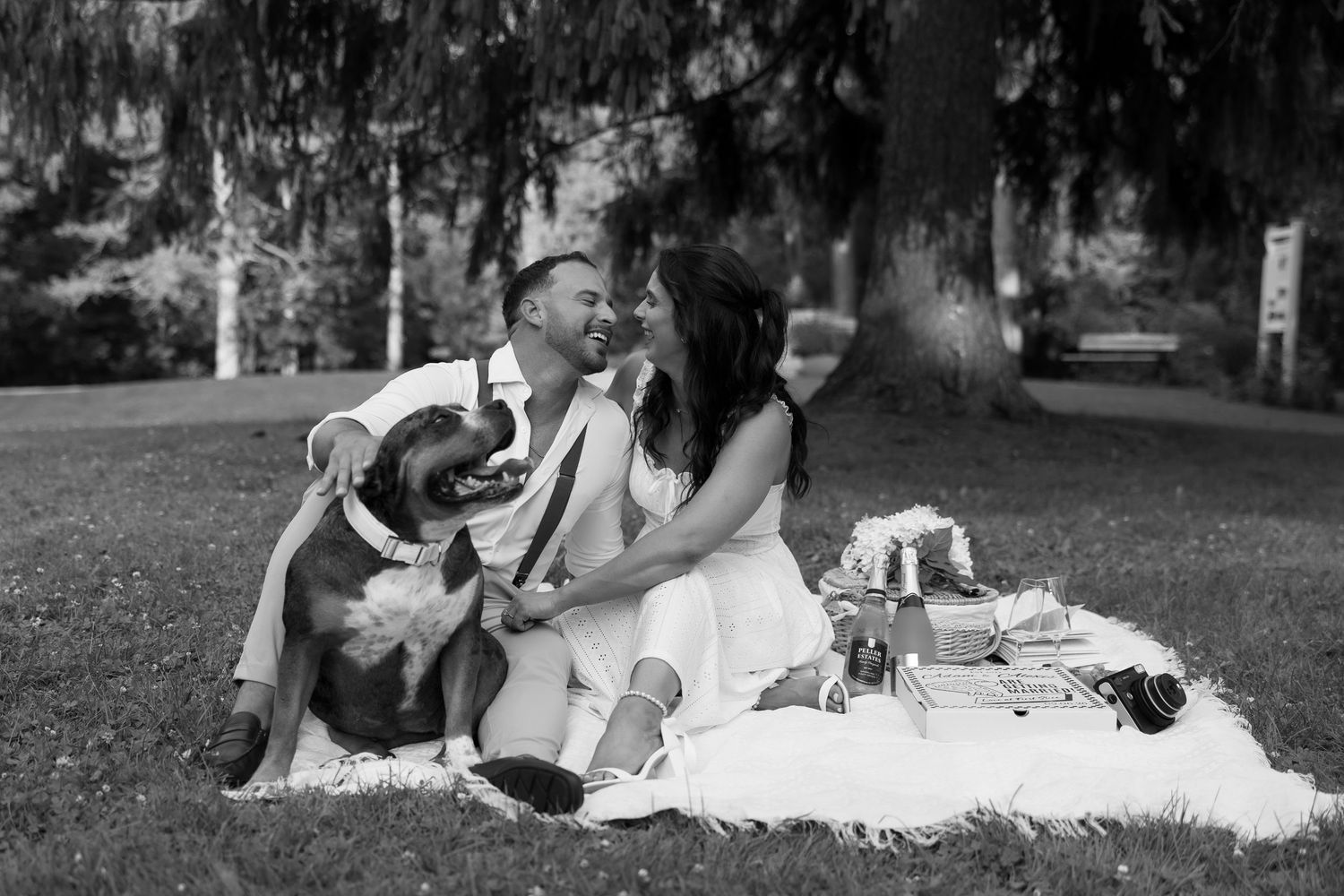 Black and white photo of couple lounging on grass during outdoor picnic.