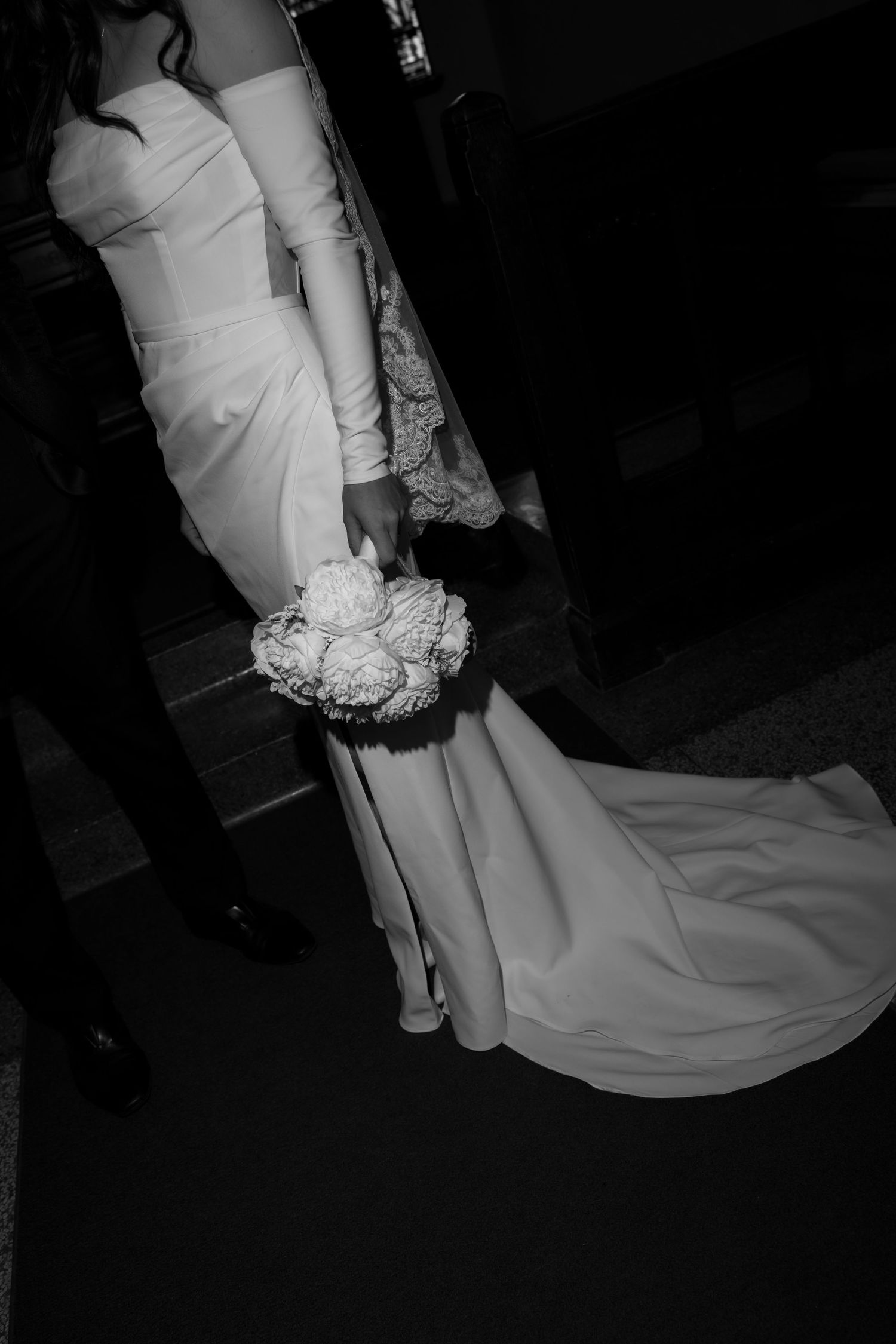 Black and white wedding dress details showing the bottom hem and ruffled layers trailing on the floor.