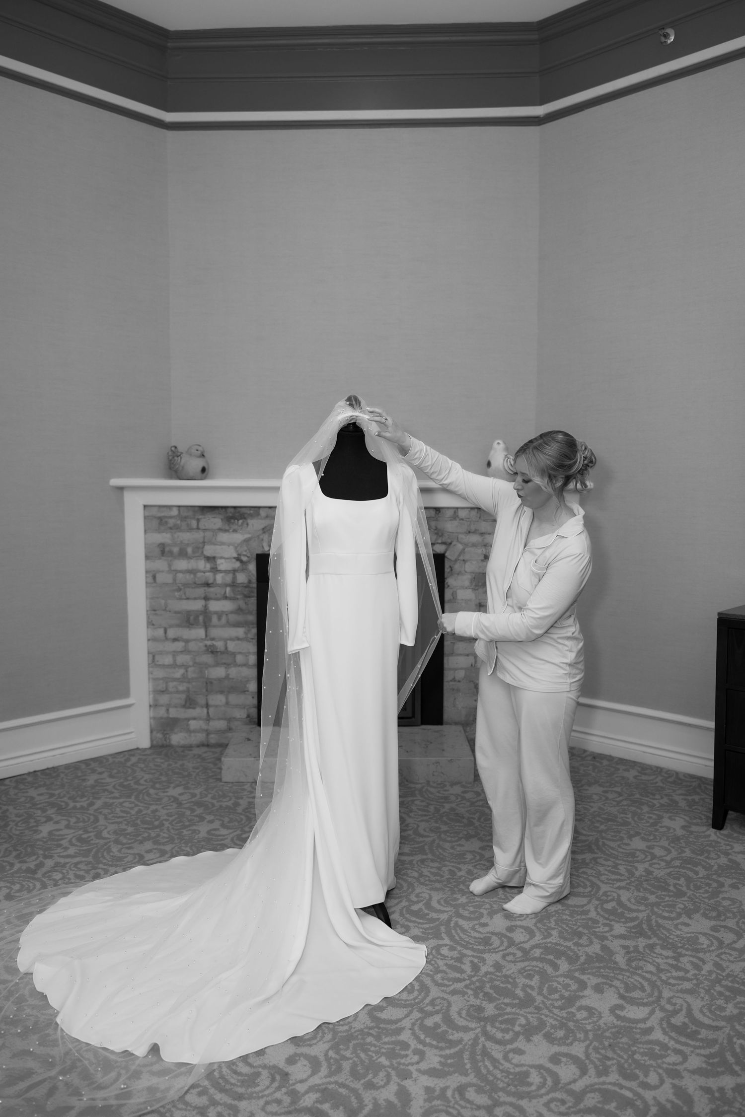 Wedding dress displayed on floor with flowing train in elegant getting ready room.