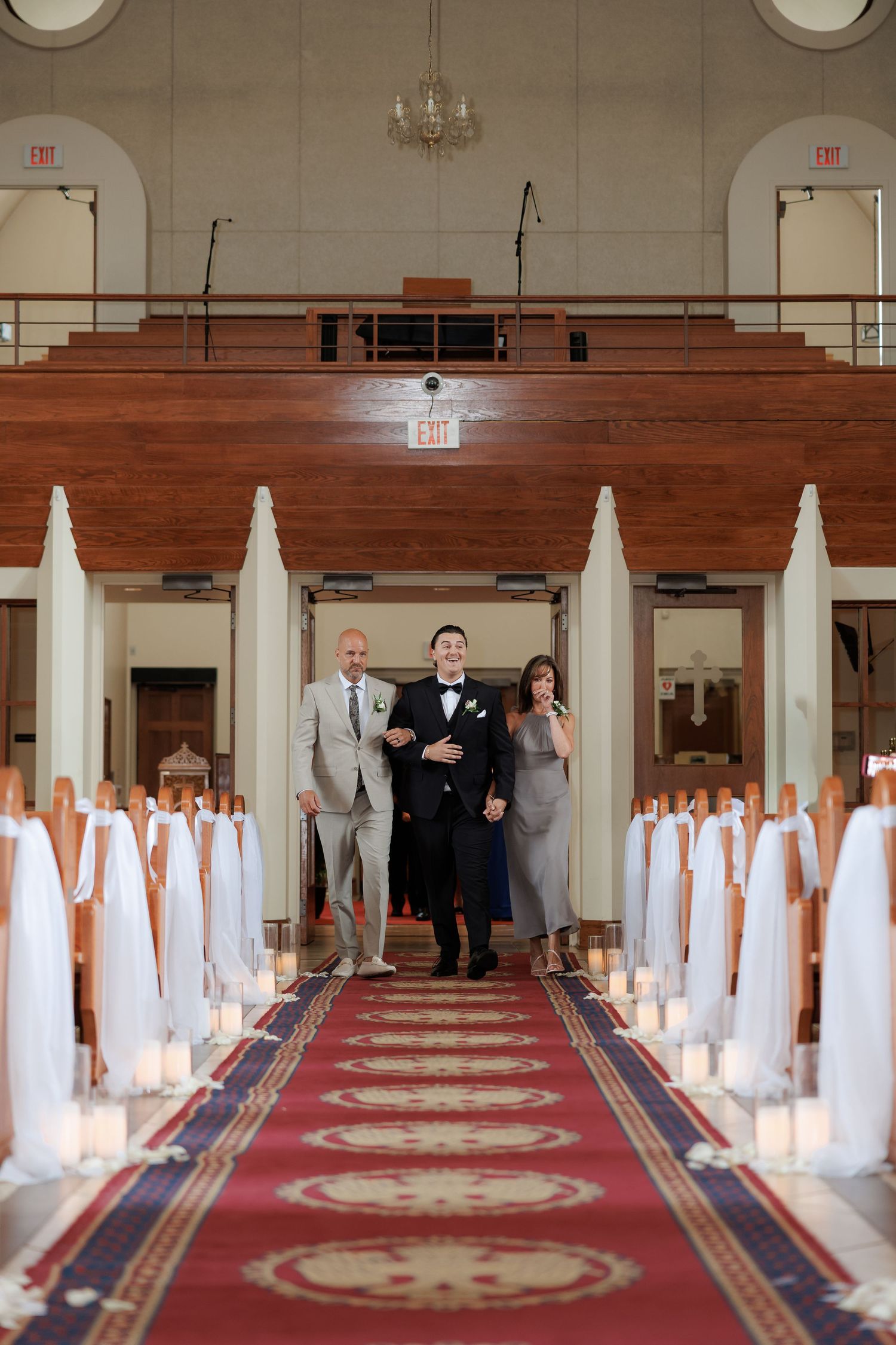 Orthodox church wedding ceremony with white decorative pillars and red carpet leading to ornate altar.