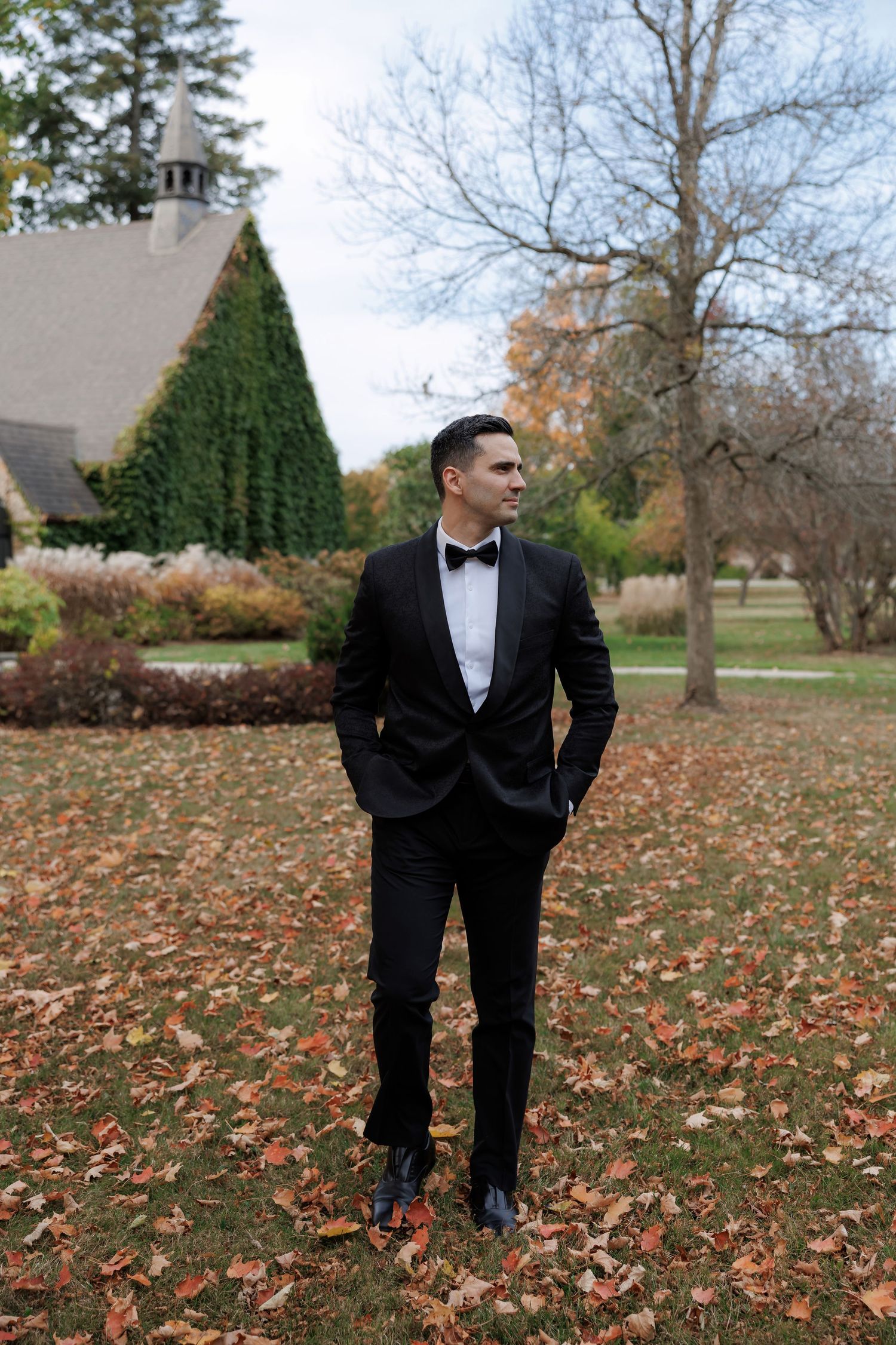Autumn wedding photos in a park with fallen leaves and trees in the background.