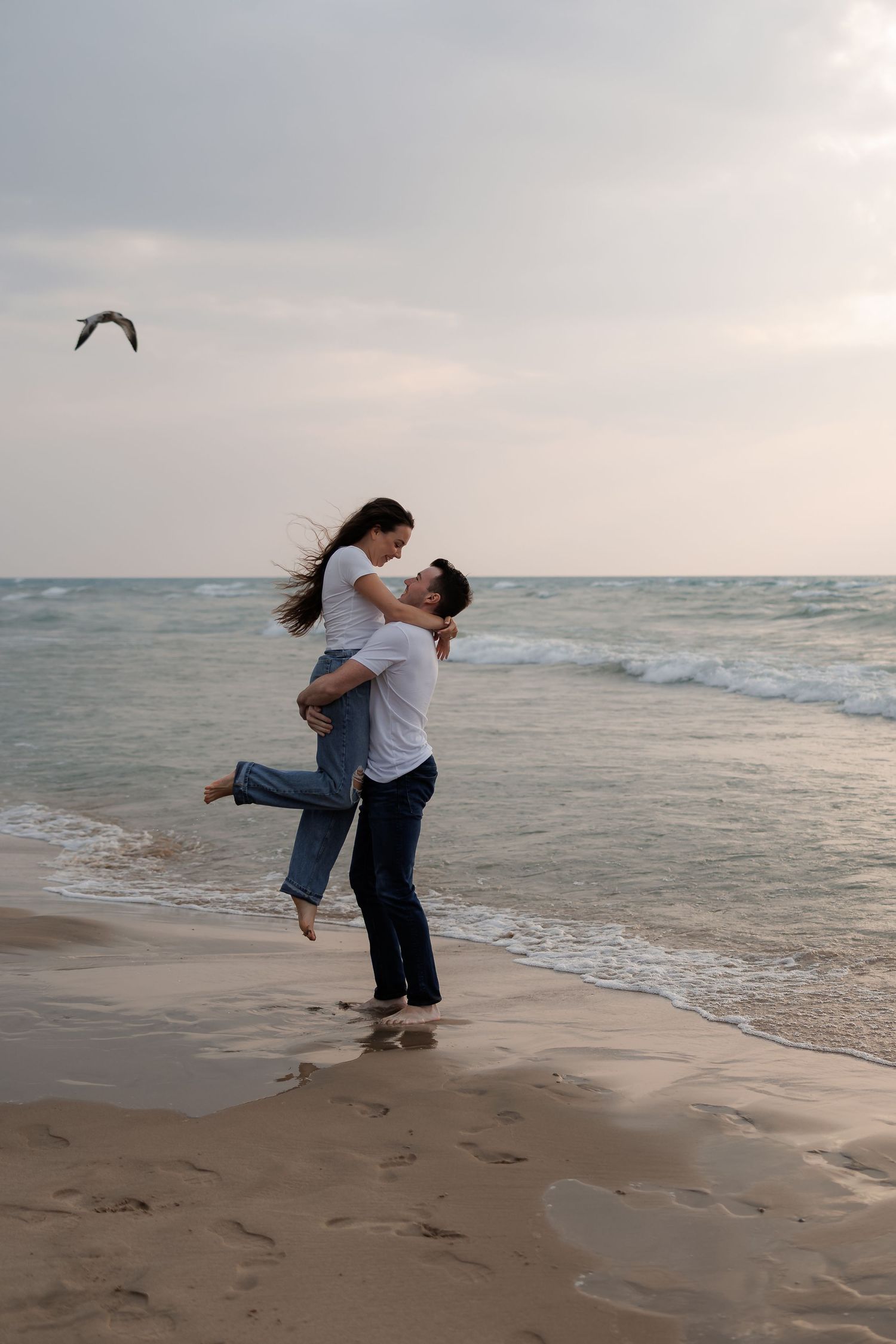 Playful couple embracing on a beach at sunset.